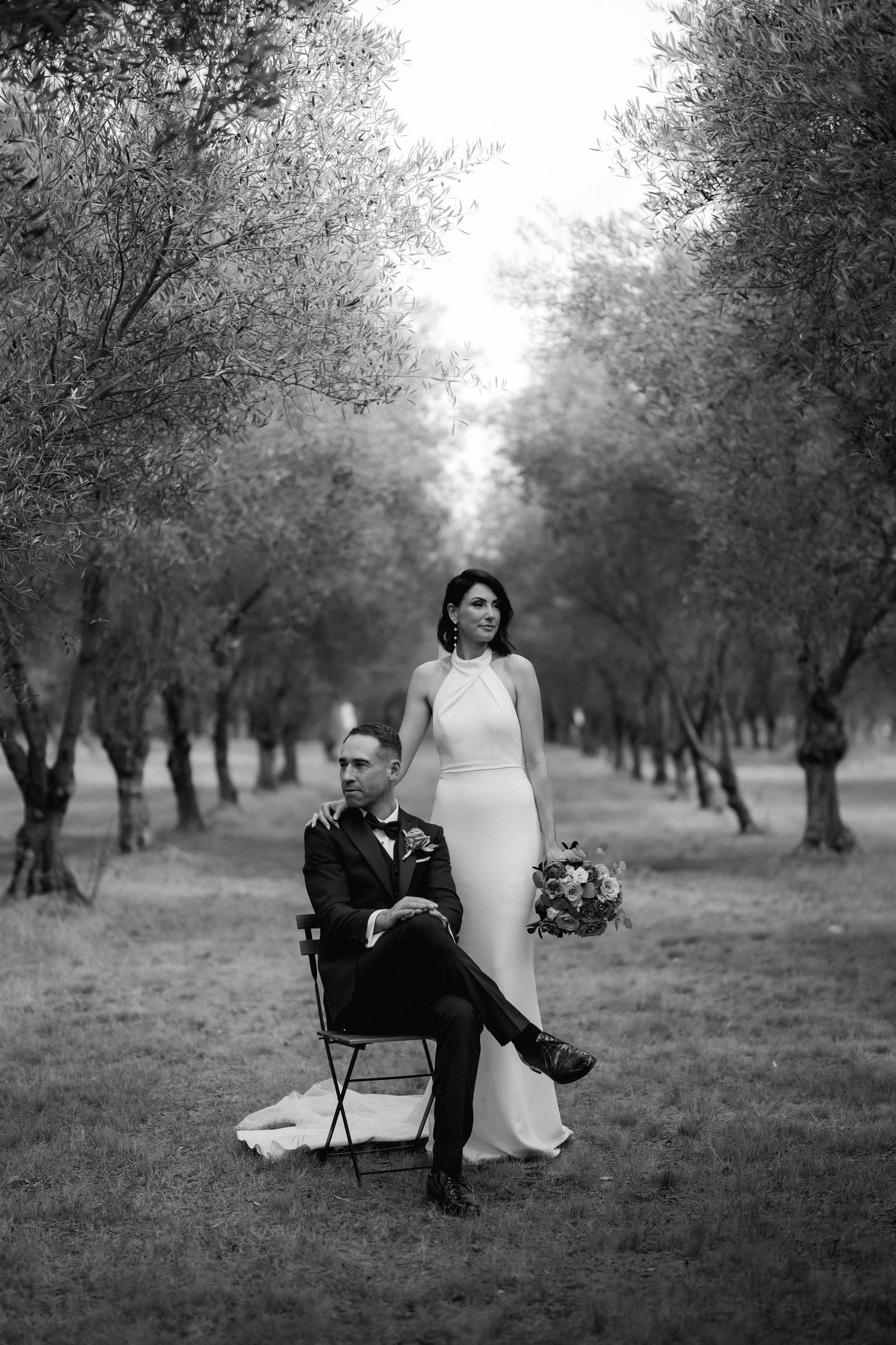 Artistic black and white wedding portrait in an olive grove with modern composition.
