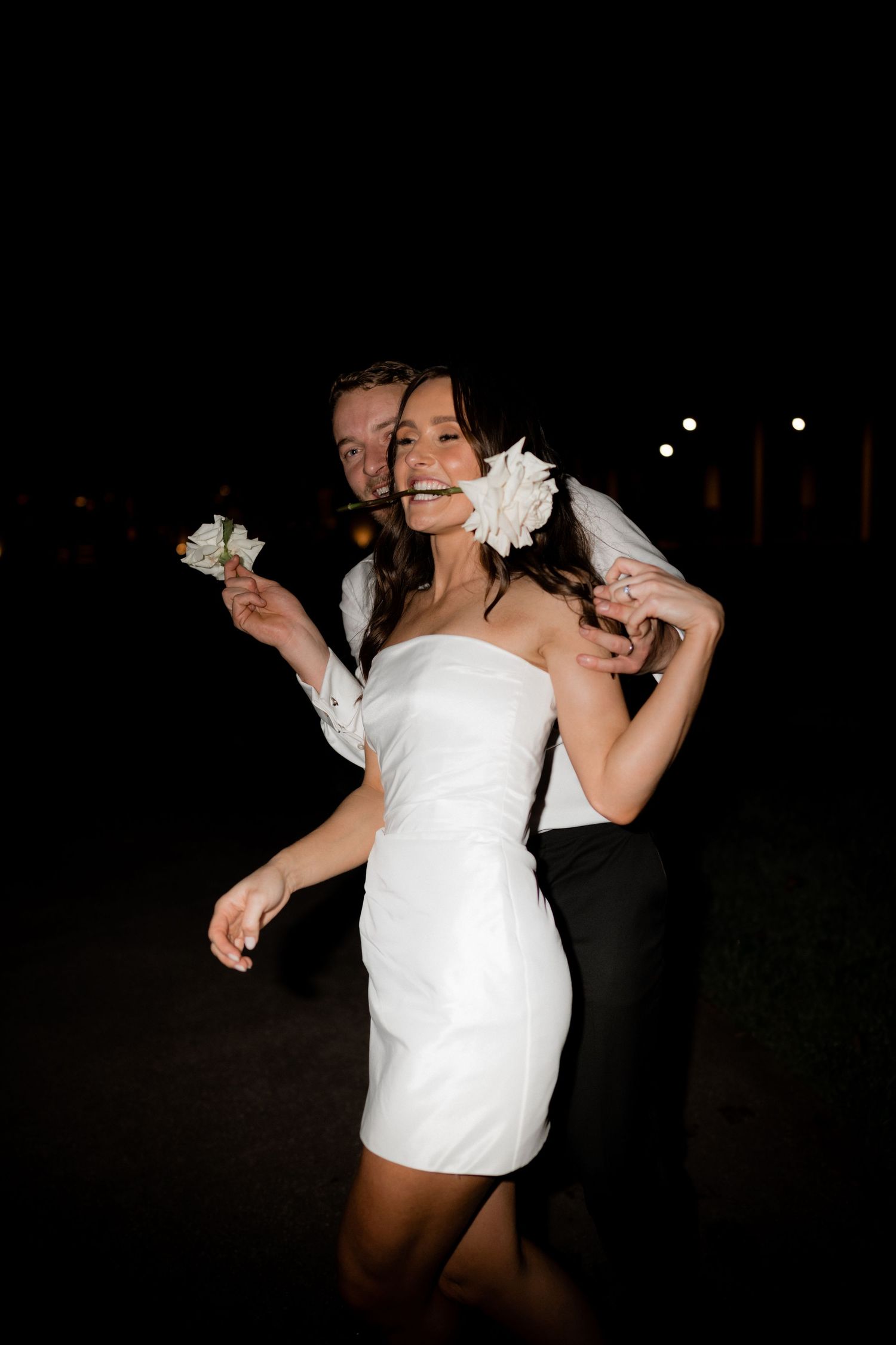 A couple shares a joyful moment on the dance floor with white flowers as decoration.