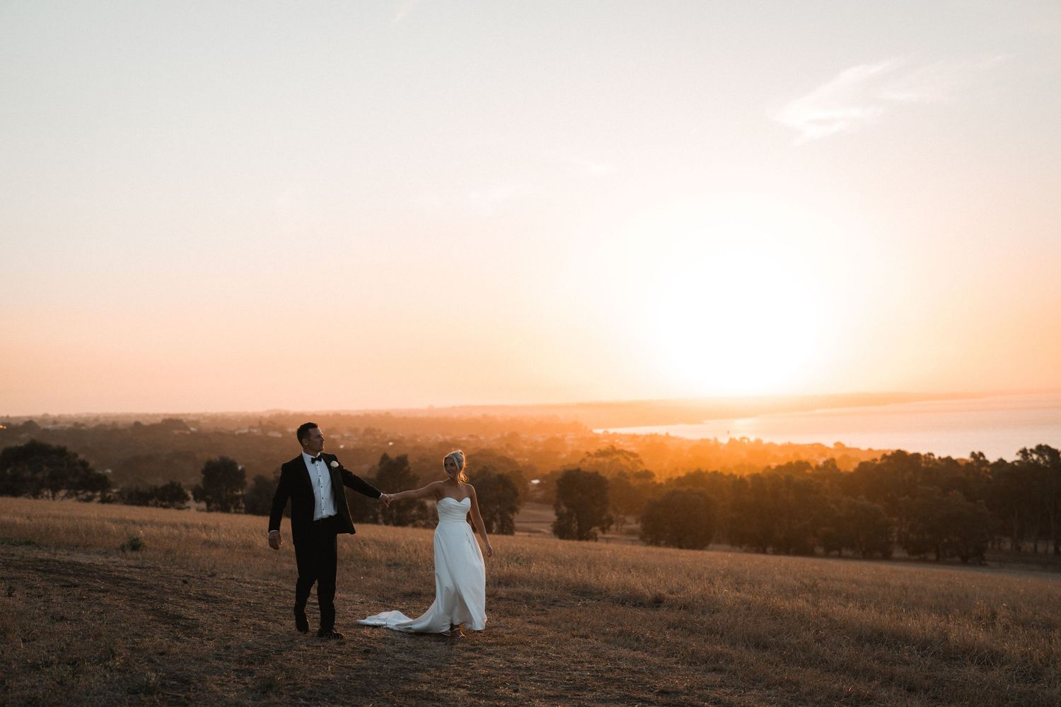 Romantic sunset wedding portrait on a hilltop overlooking a valley.