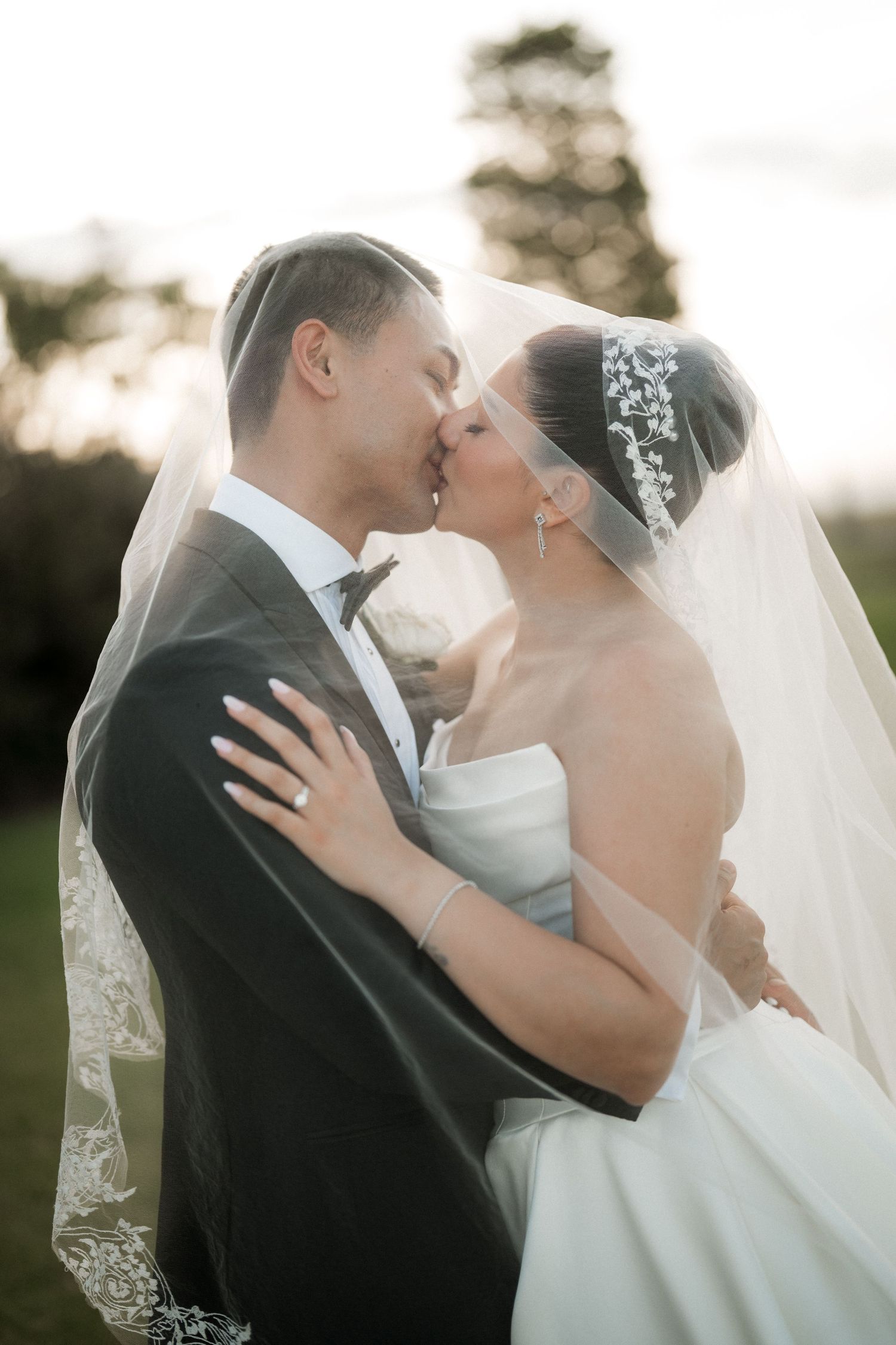Romantic wedding portrait of couple sharing intimate moment with flowing veil.