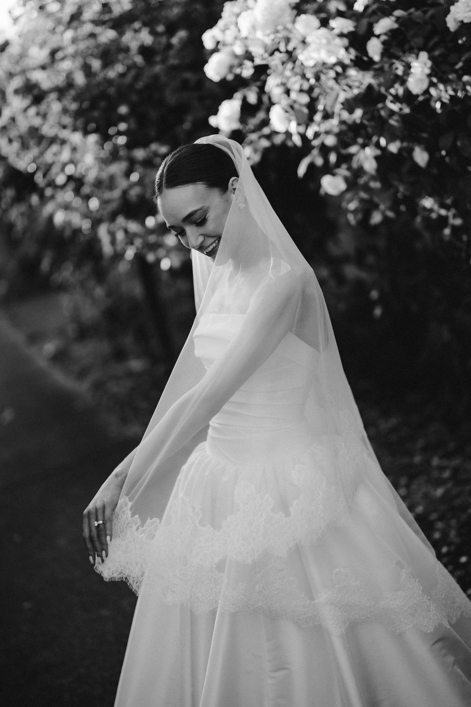 Black and white photos of flowing wedding dress details in garden setting.