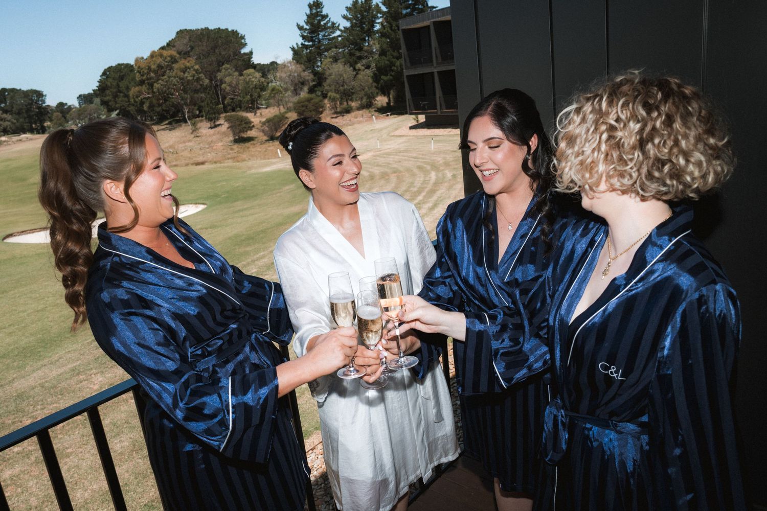 A group wearing white and navy blue formal attire interacts outdoors during a special occasion.