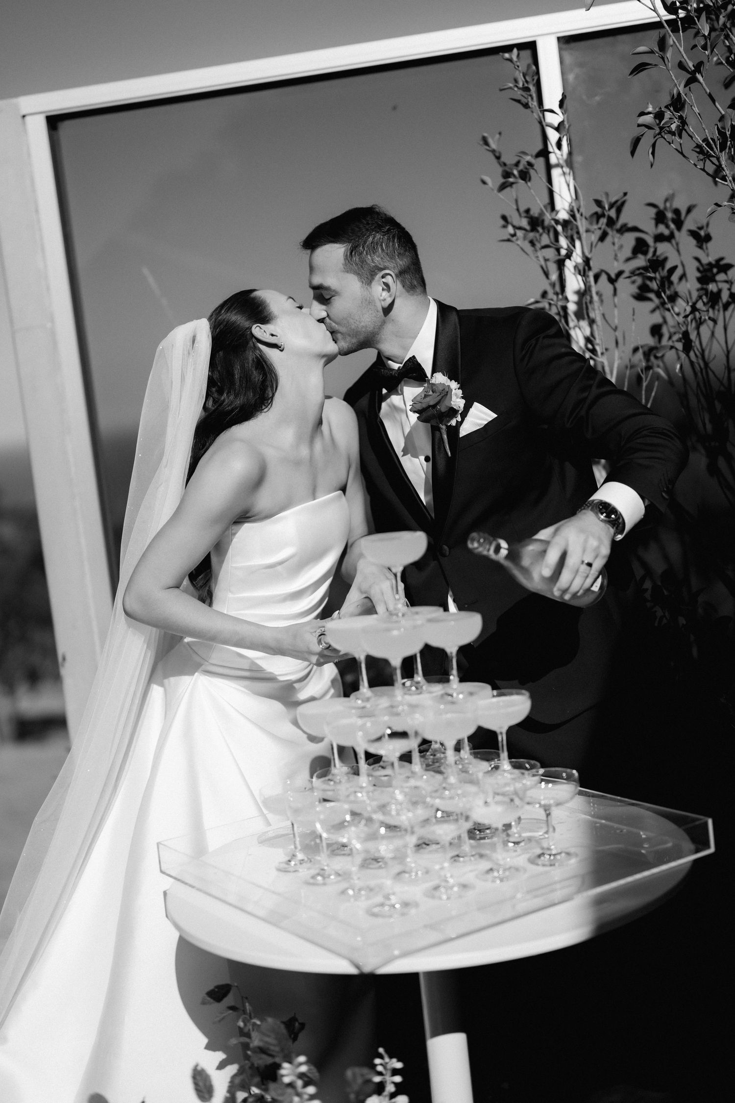 Wedding couple sharing a champagne toast with multiple glasses on a serving tray.