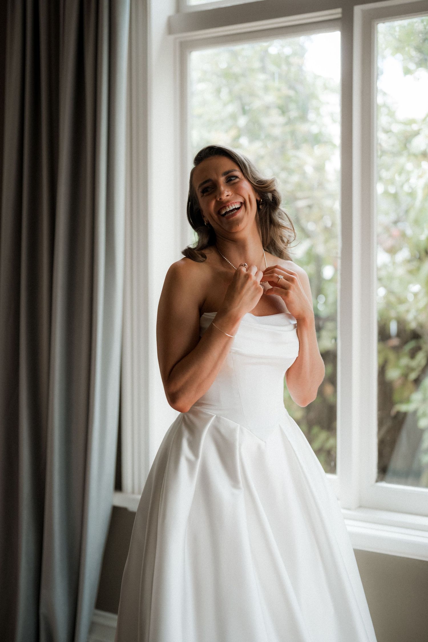 A sequence showing a joyful bride in a white wedding dress laughing and twirling in front of windows.