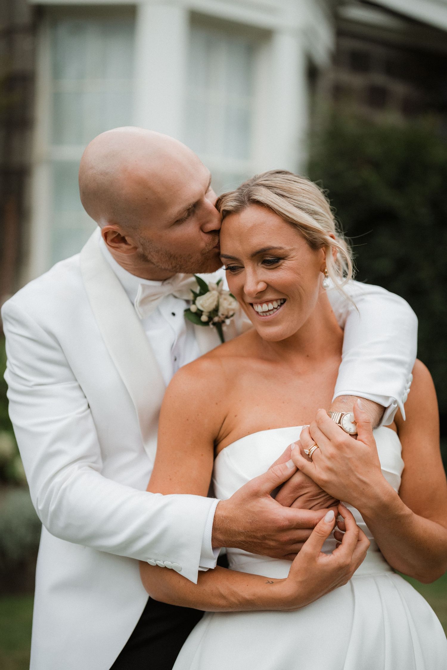 Romantic moment between newlyweds in white attire.