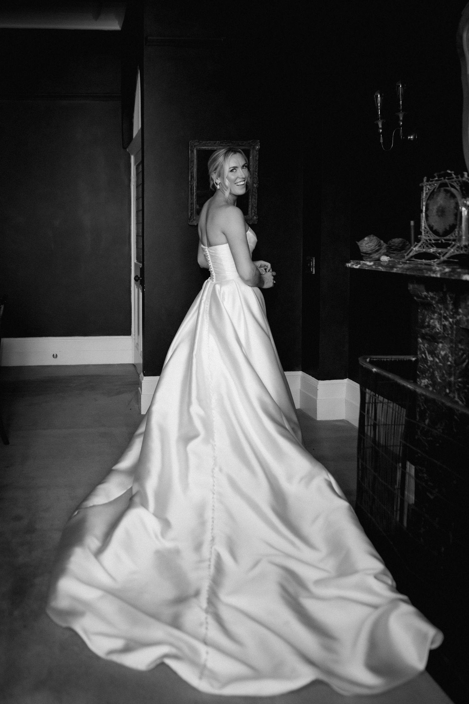 A stunning wedding dress with a dramatic long train captured in a moody black and white photograph.