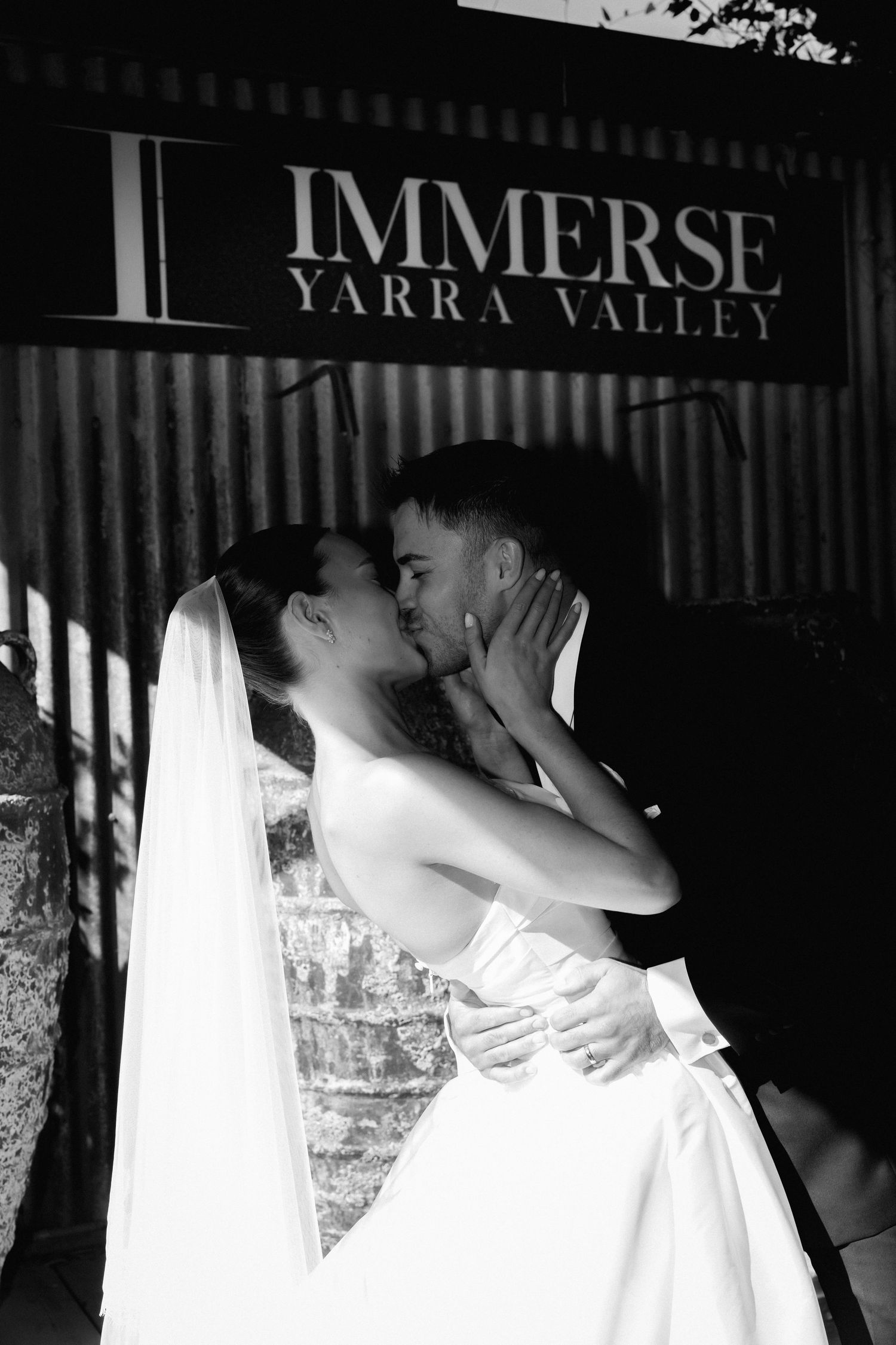 A romantic black and white wedding photo under the Immerse Yarra Valley sign.