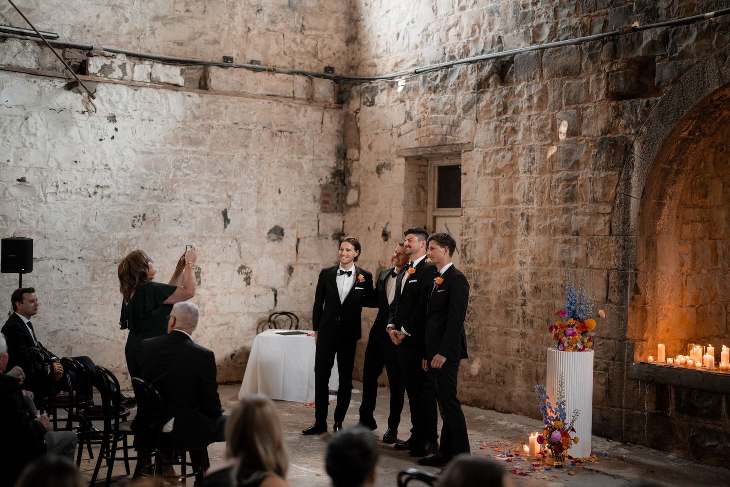 Wedding ceremony setup in a rustic stone-walled venue with candlelight.