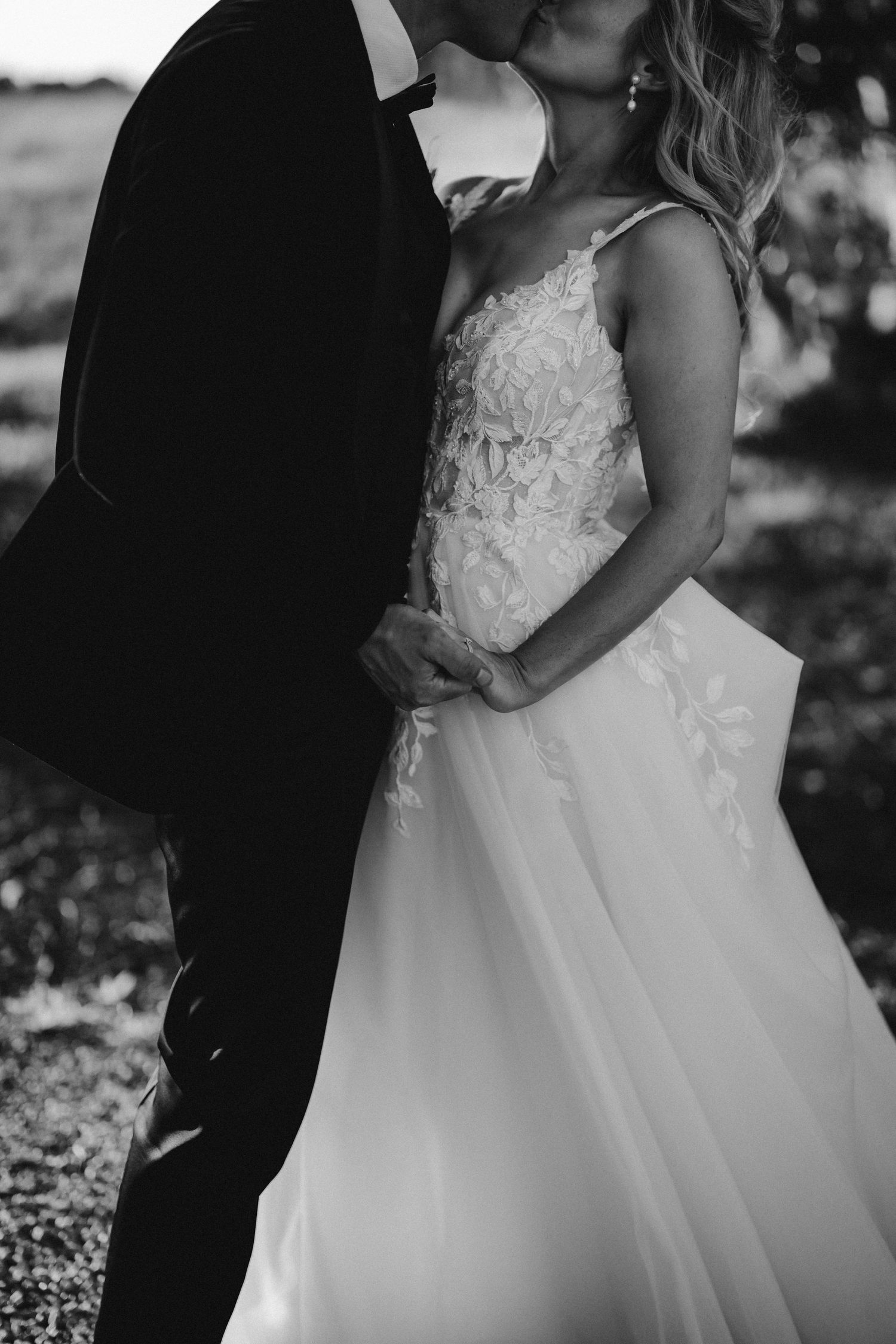 Black and white intimate portrait of a couple embracing in formal wedding attire.