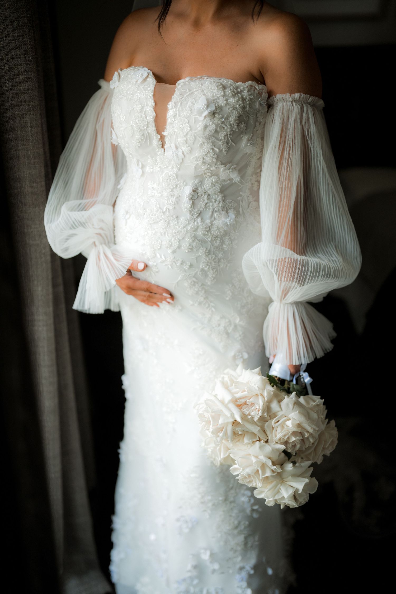 Elegant white wedding dress with lace details and sheer billowing sleeves shown in close-up shots.