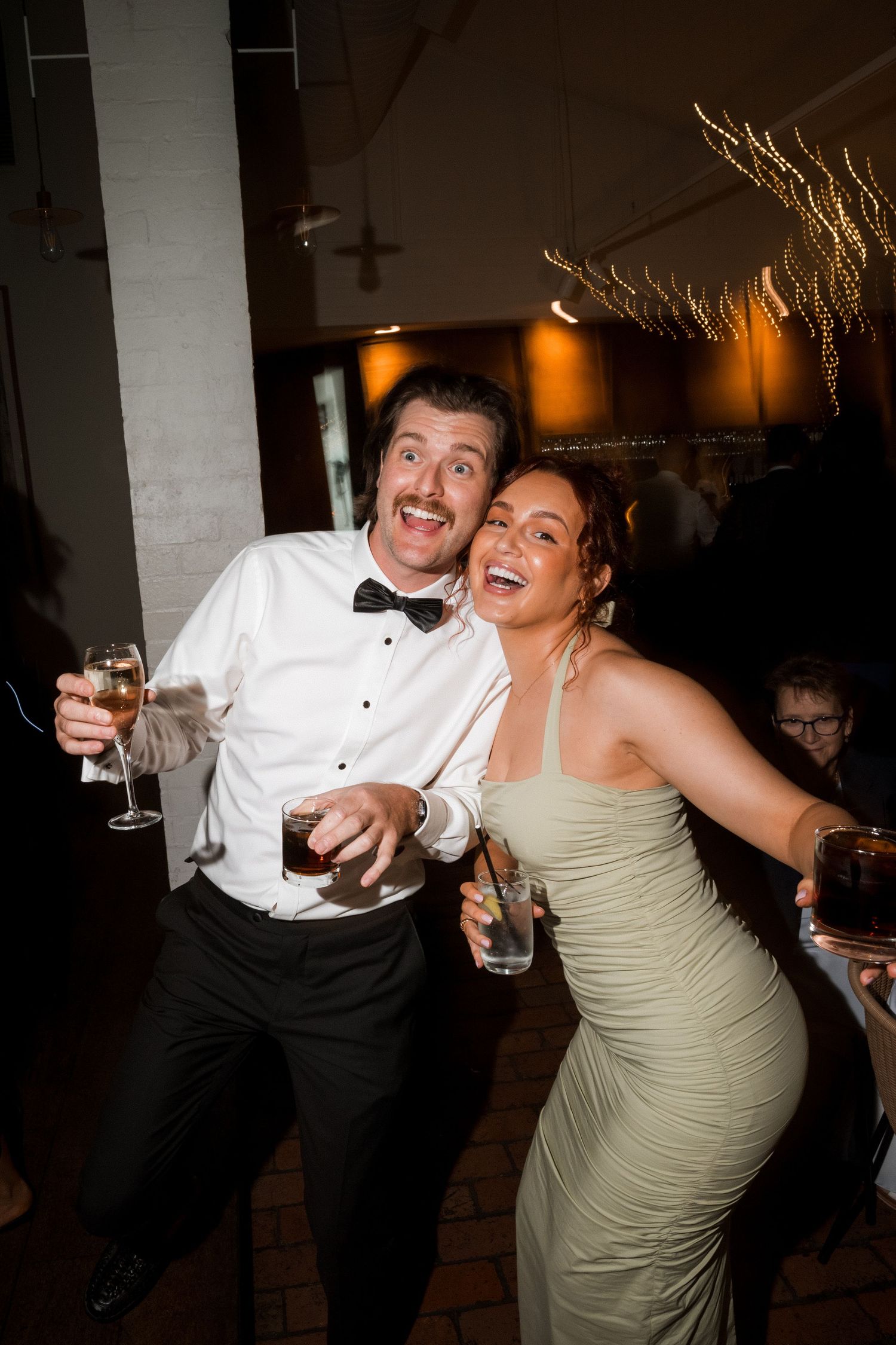 Wedding guests dancing and celebrating at a dimly lit reception party.