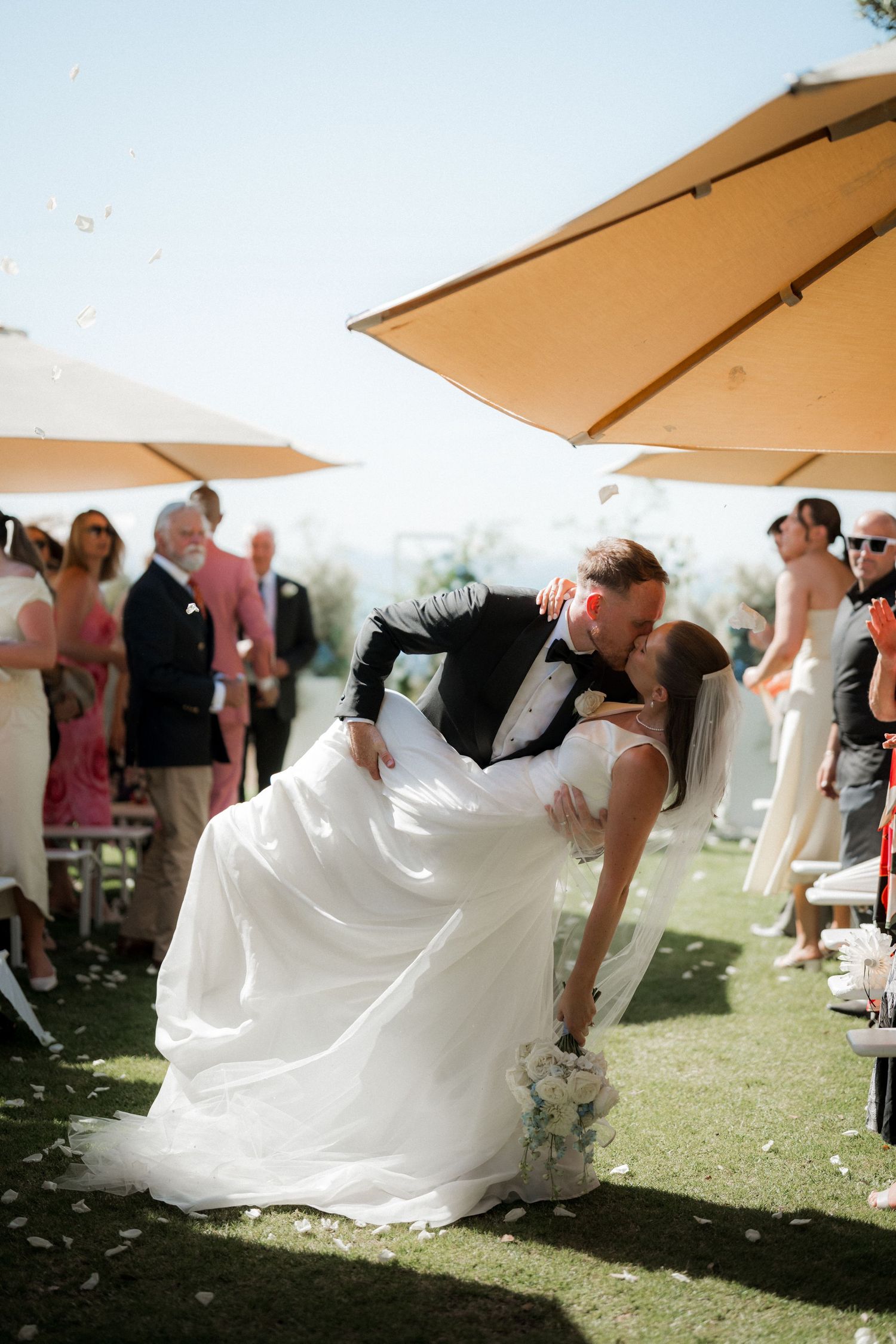 A sequence of wedding photos showing a couple performing a dramatic dip dance move under outdoor umbrellas.