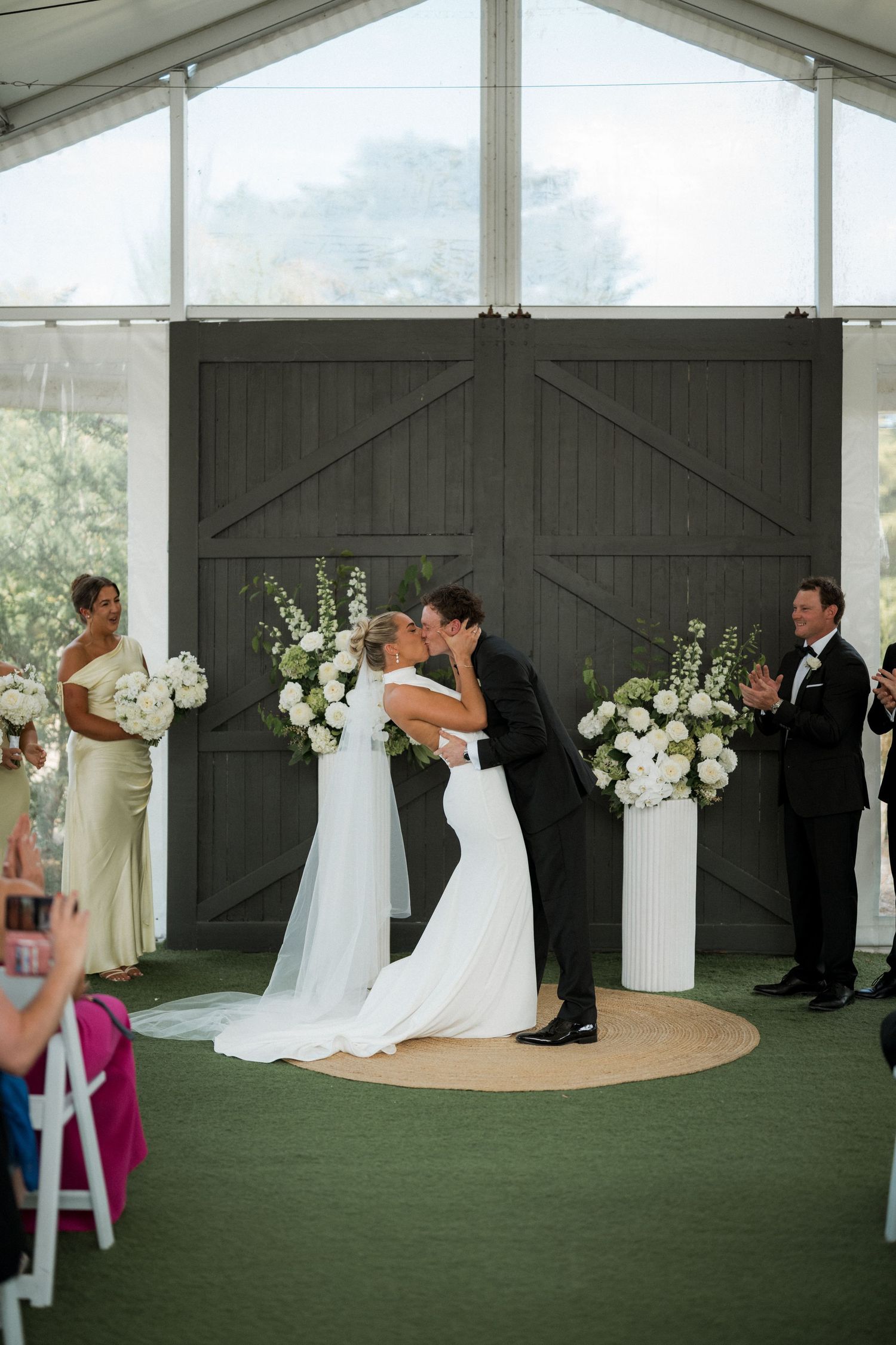 Wedding ceremony setup in an elegant indoor venue with white floral arrangements and green carpet.