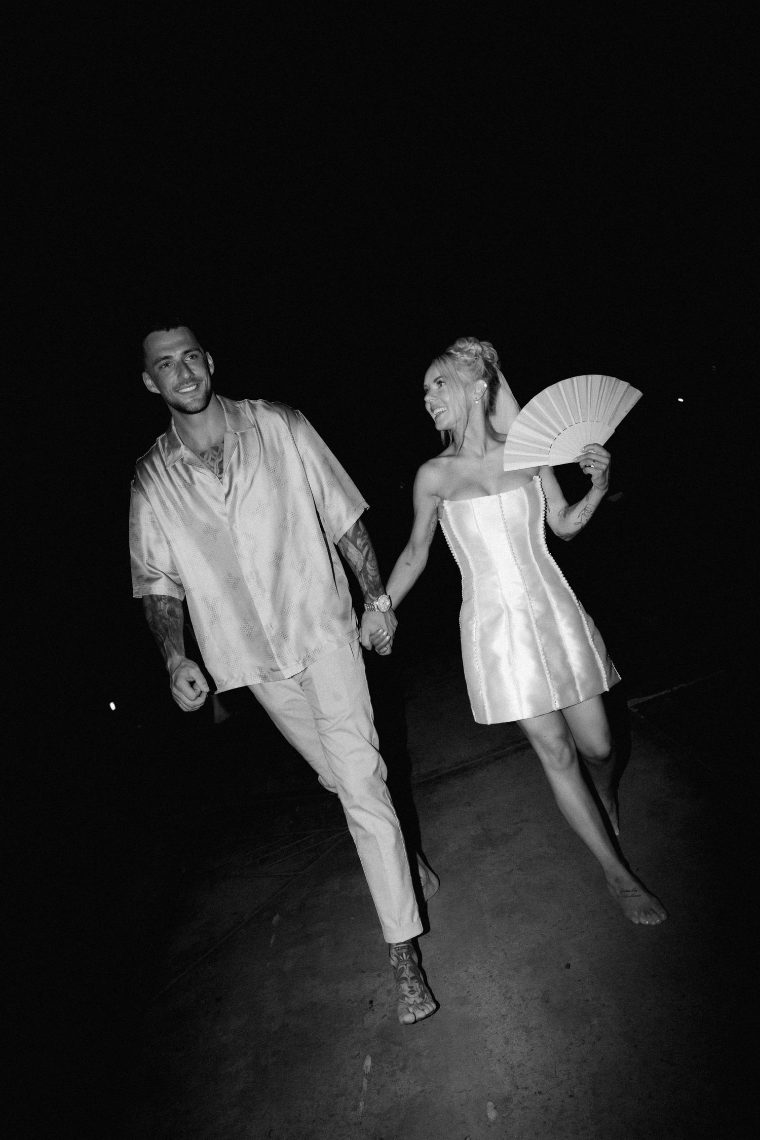Black and white photo of a playful moment showing a couple dancing in casual evening attire.