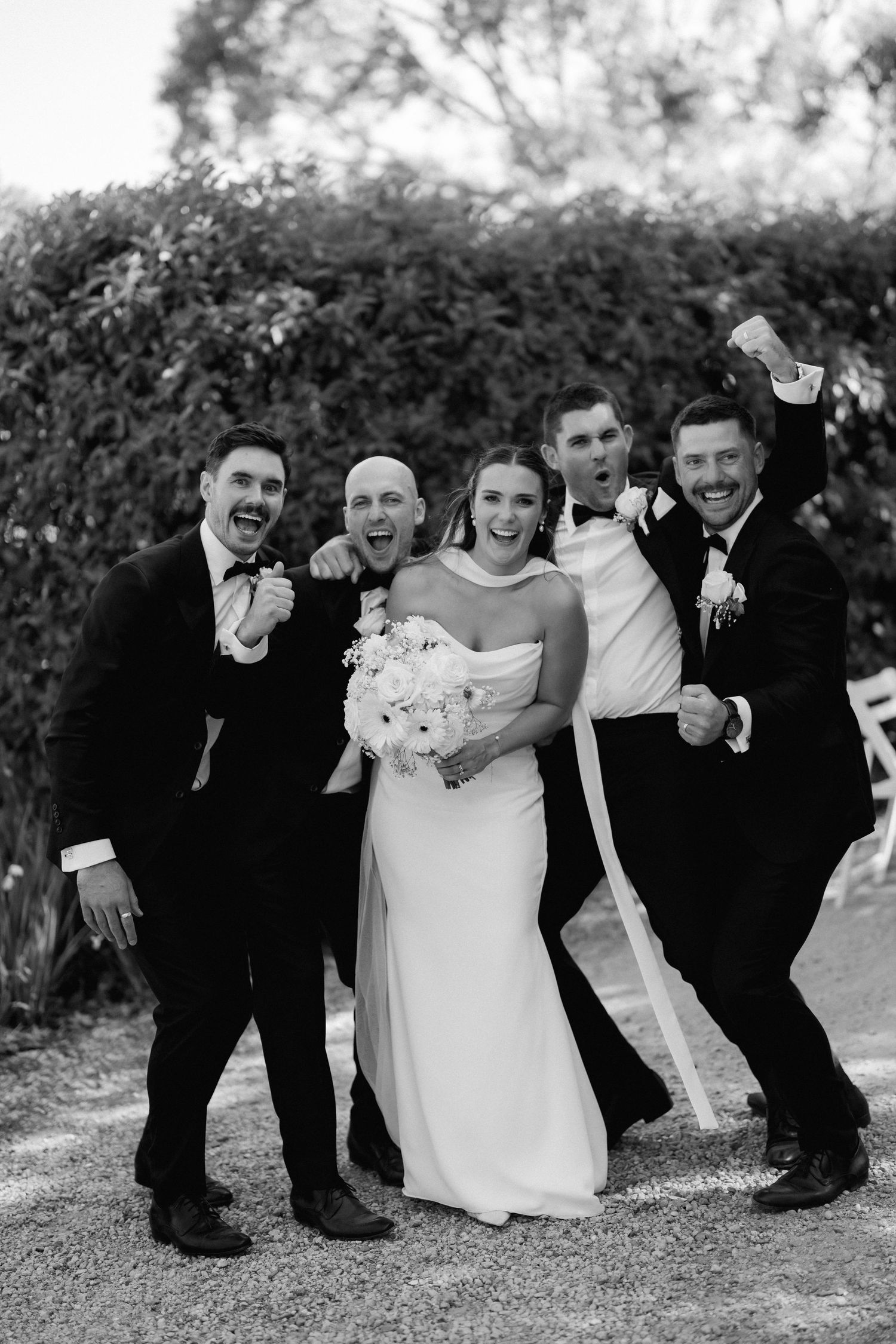 Black and white photos of wedding party posing playfully outdoors with creative group shots.