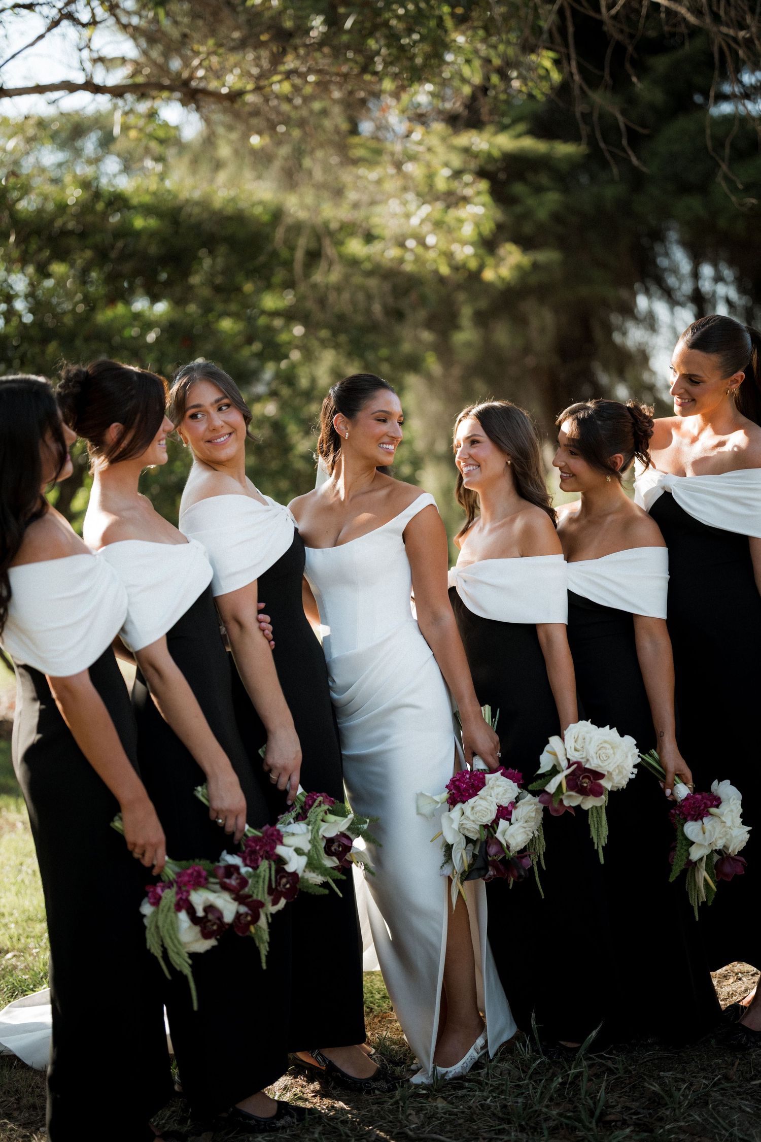 Wedding party in black and white dresses standing together outdoors.