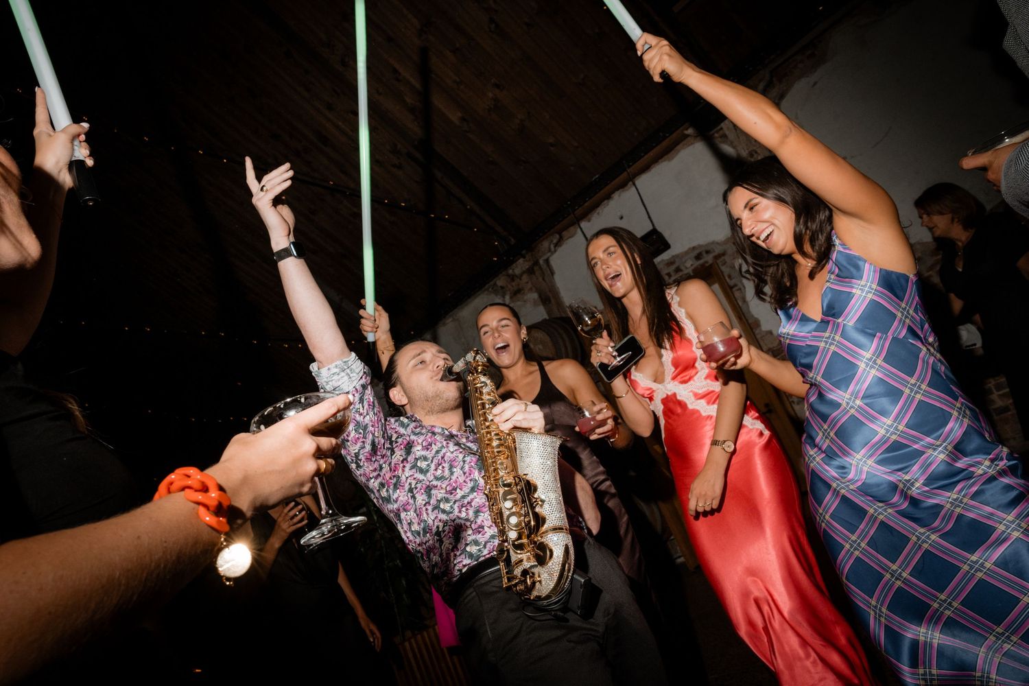 Energetic dance floor scene with guests holding glow sticks during wedding reception celebration.