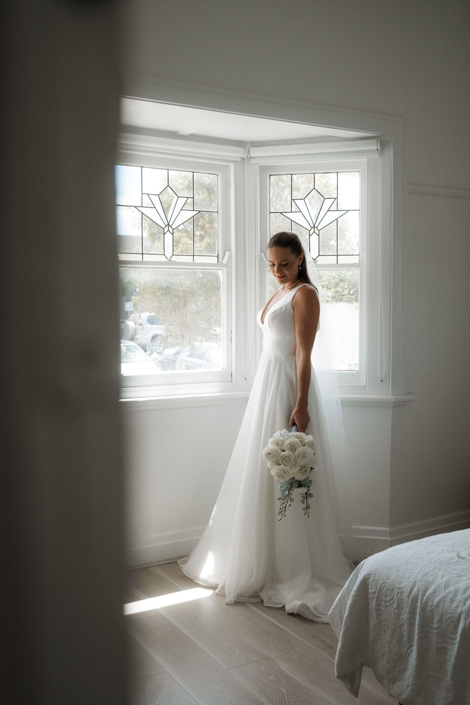 Ethereal bridal portraits in a sunlit room with white walls and decorative windows creating a dreamy atmosphere.