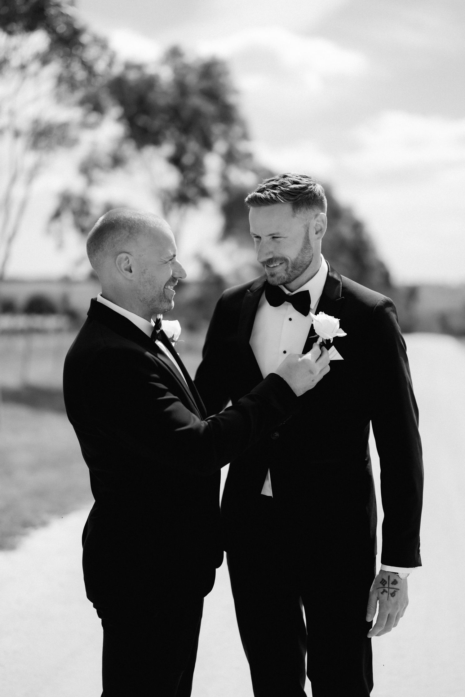 Two people in formal tuxedos share an intimate moment during a wedding ceremony.
