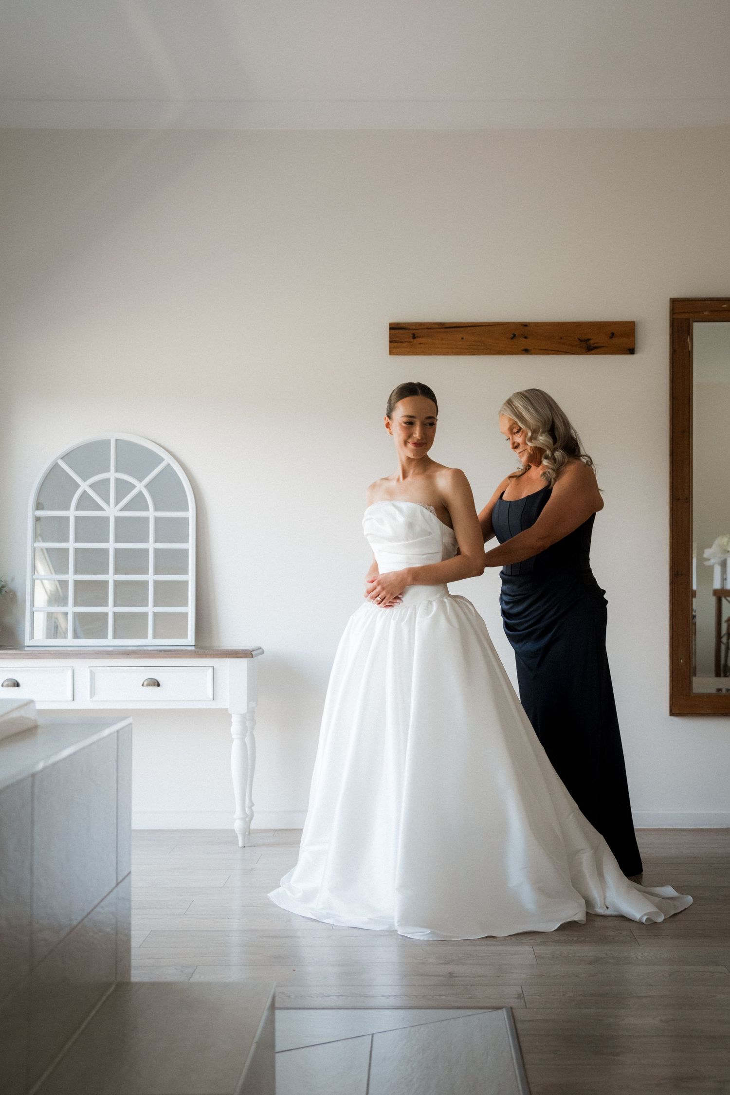 Series of photos showing preparation with white wedding dress in modern venue.