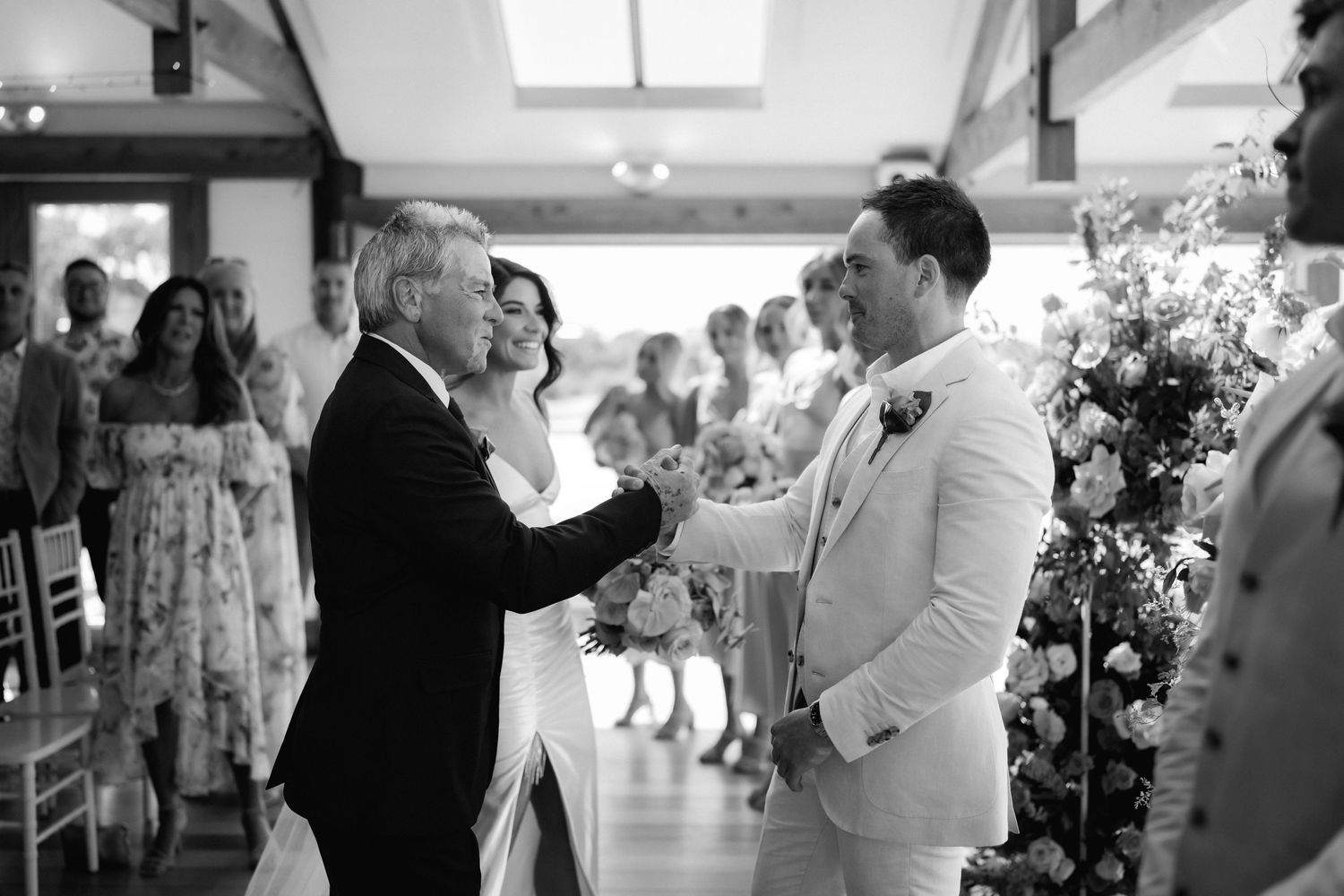 Wedding guests gathered in an indoor reception venue with bright lighting.