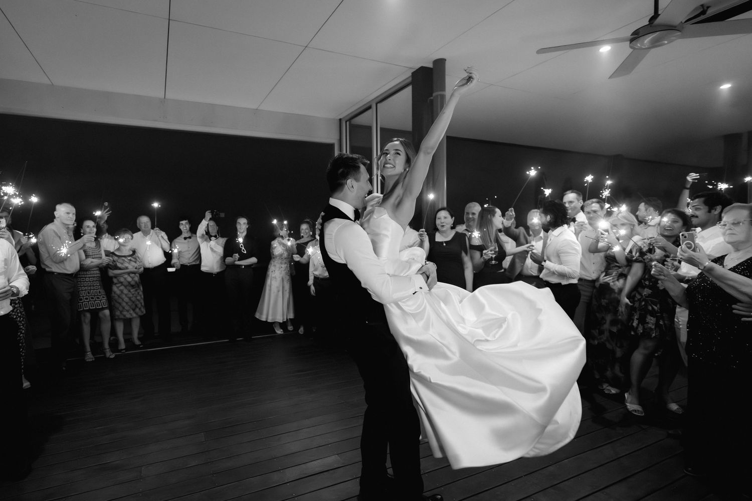 A series of black and white photos showing a couple dancing at a wedding reception celebration with guests watching.