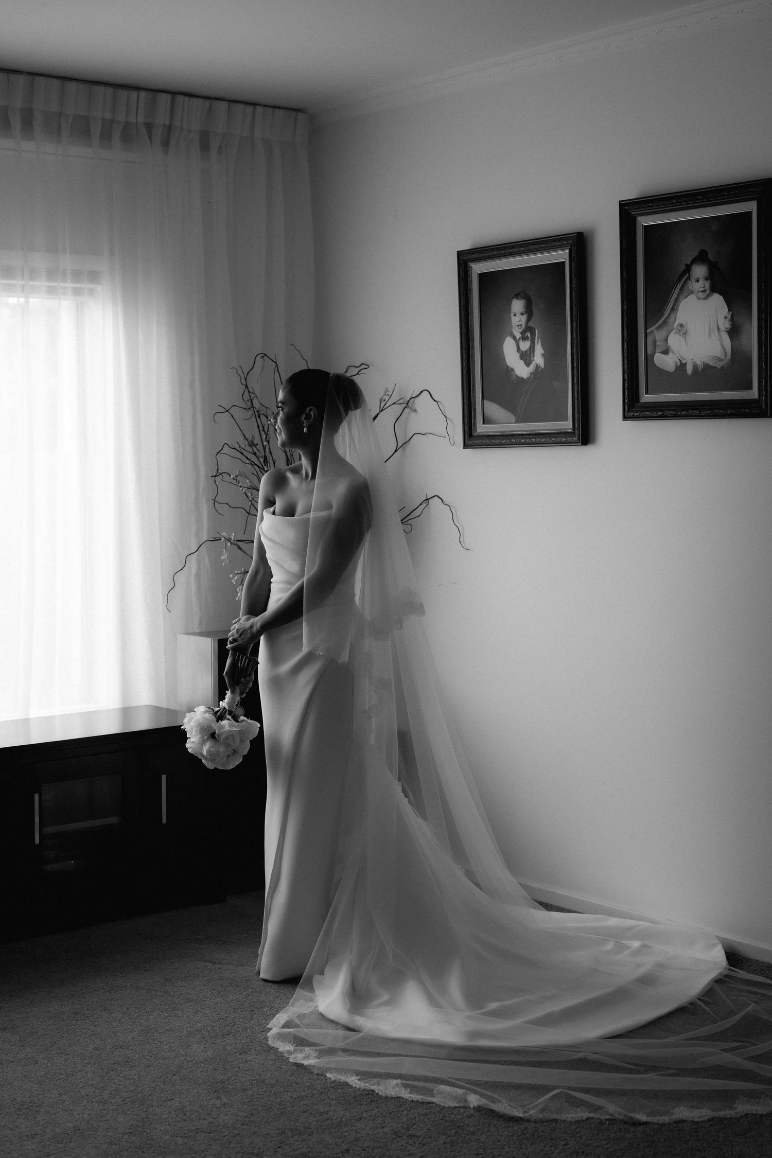 Black and white sequence showing bride's dress and veil movement in a sunlit room with framed photos.