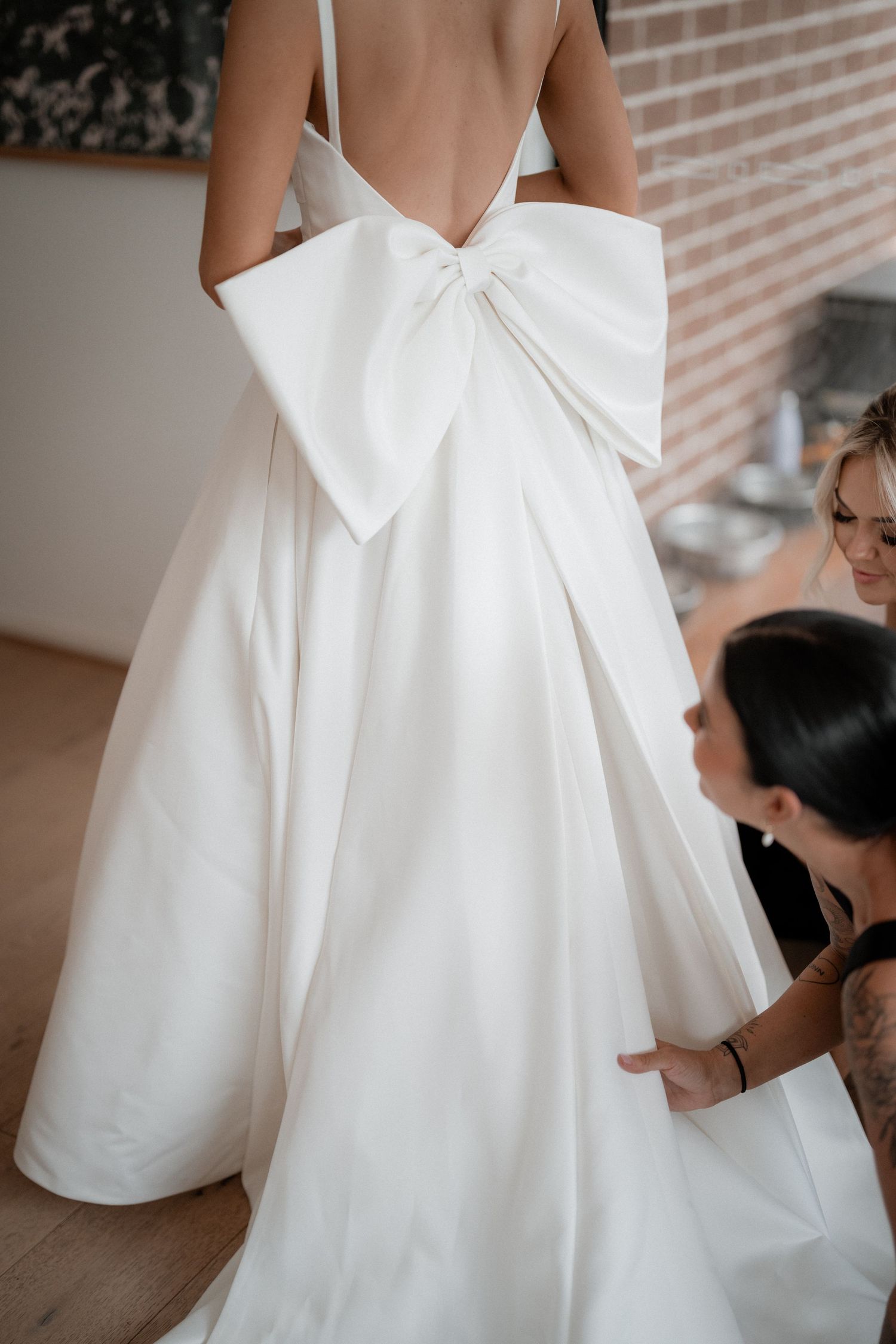 Close-up details of a white wedding dress with elegant bow accents at back.