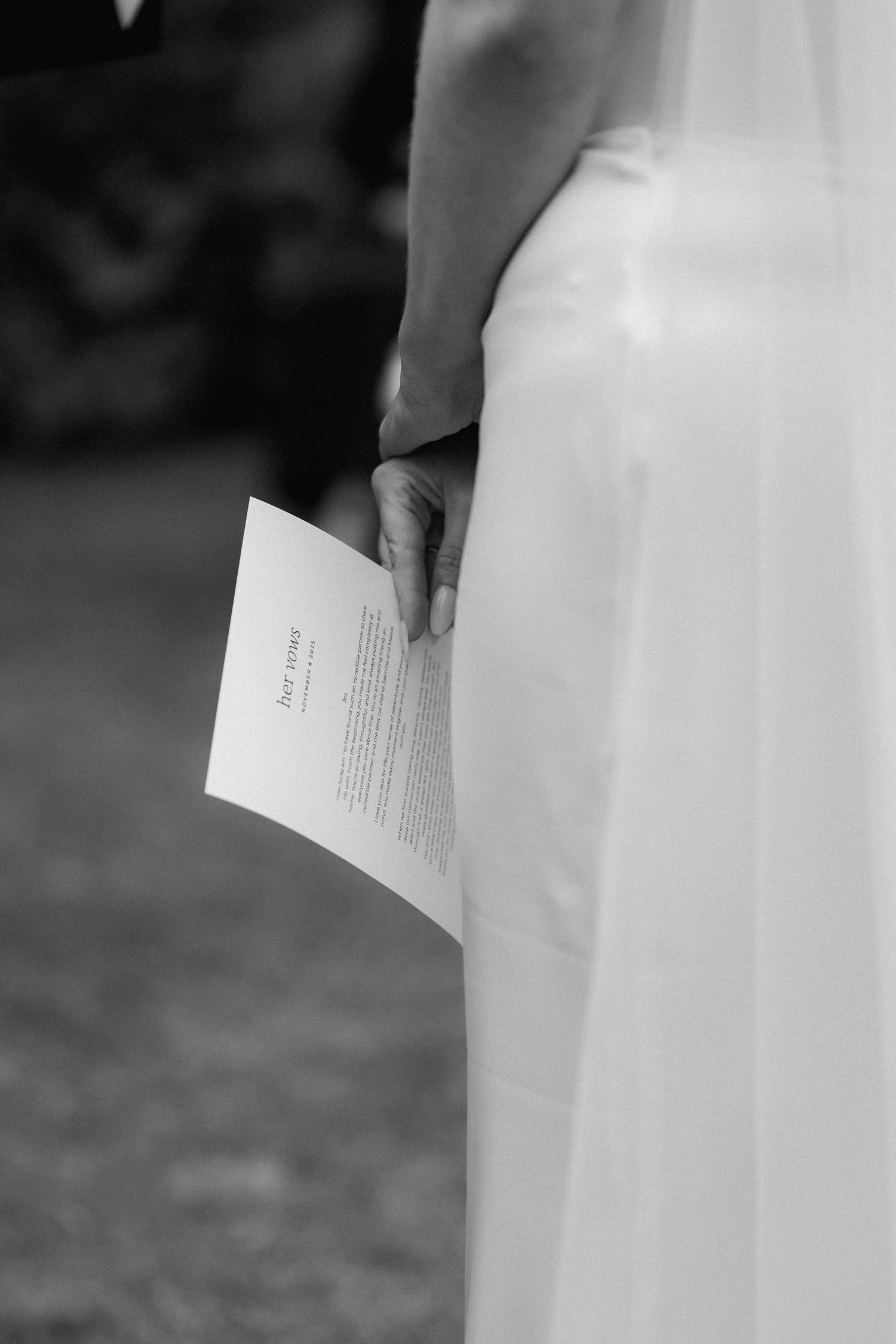 A black and white photo shows hands holding and reading through pages of a document or letter.