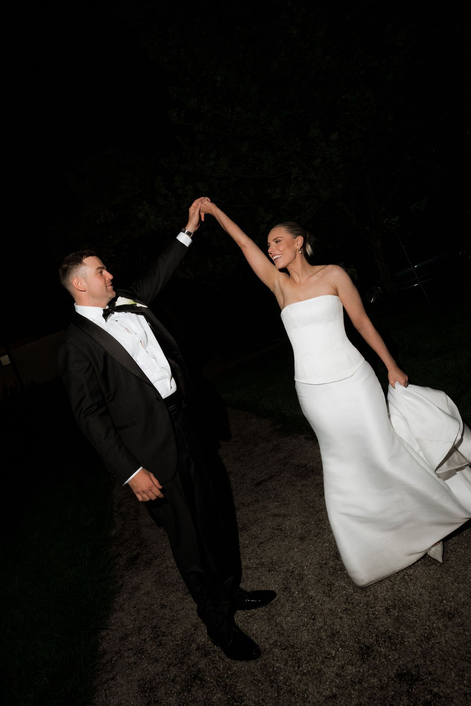 A couple performs a dramatic dip dance move during their wedding celebration at night.