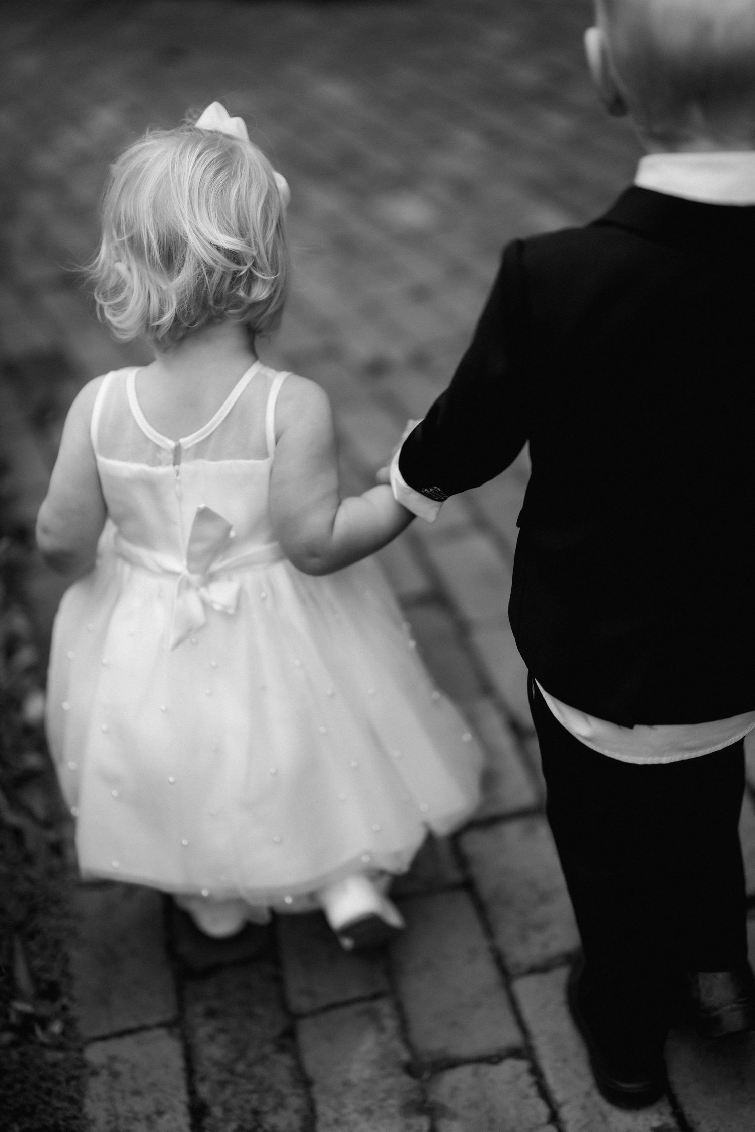 Series of black and white photos showing a small child in a white dress walking with an adult in formal wear.