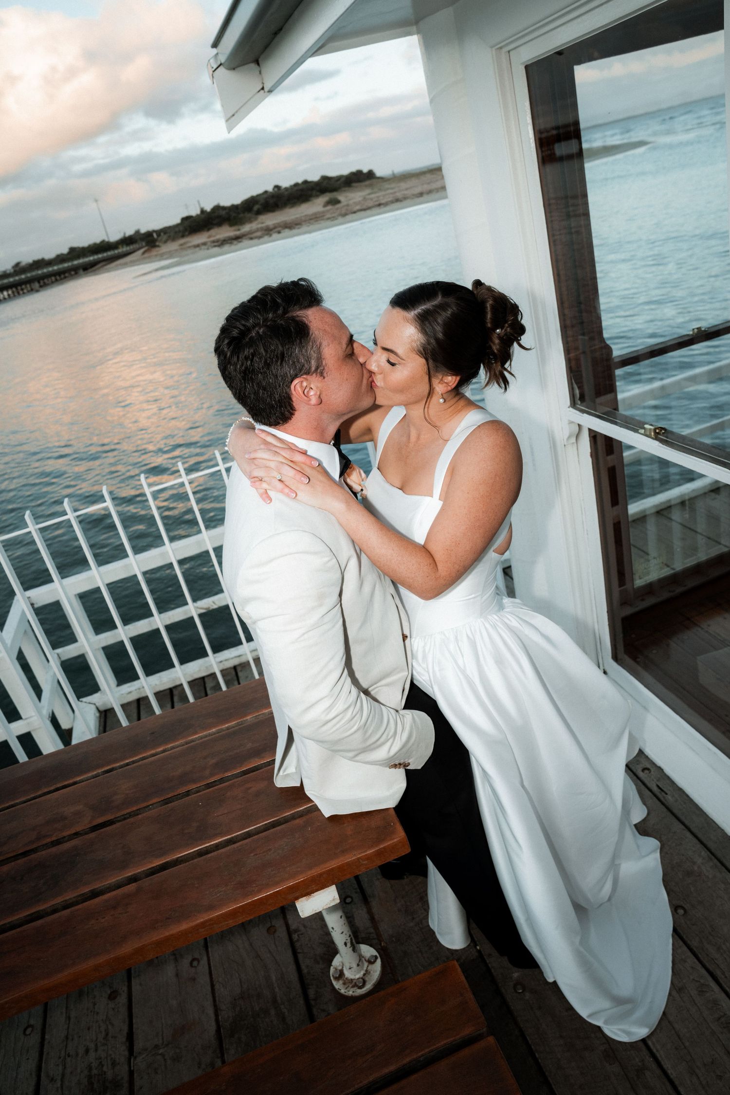 Romantic sunset moment on a waterfront deck with white railing.