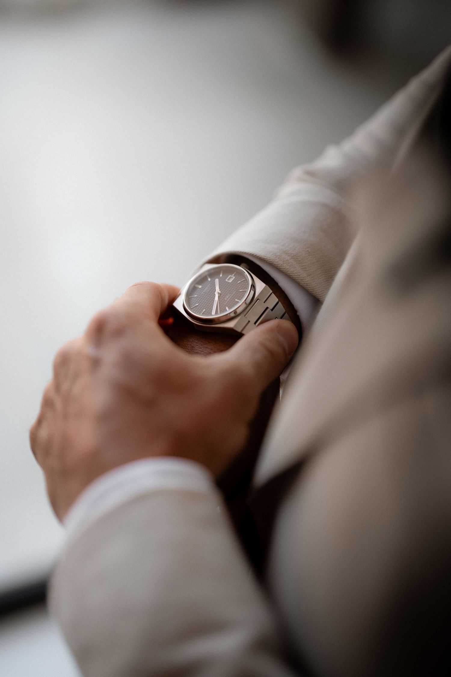 Close-up detail of a wristwatch being checked against time on a formal occasion.