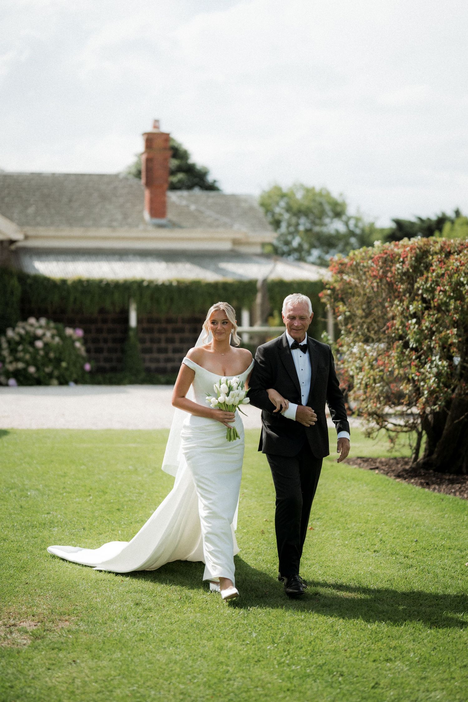 Wedding couple walks and poses together on sunny green lawn.
