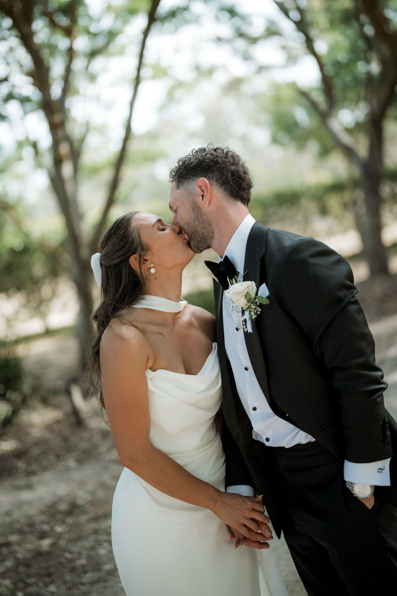 A romantic wedding couple shares intimate kisses in a series of black and white photographs outdoors.