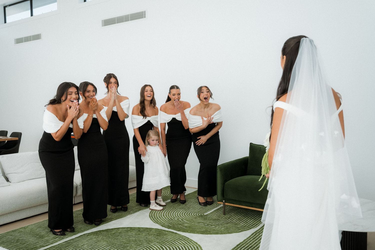 Wedding party poses together in a modern white room with black and white attire.