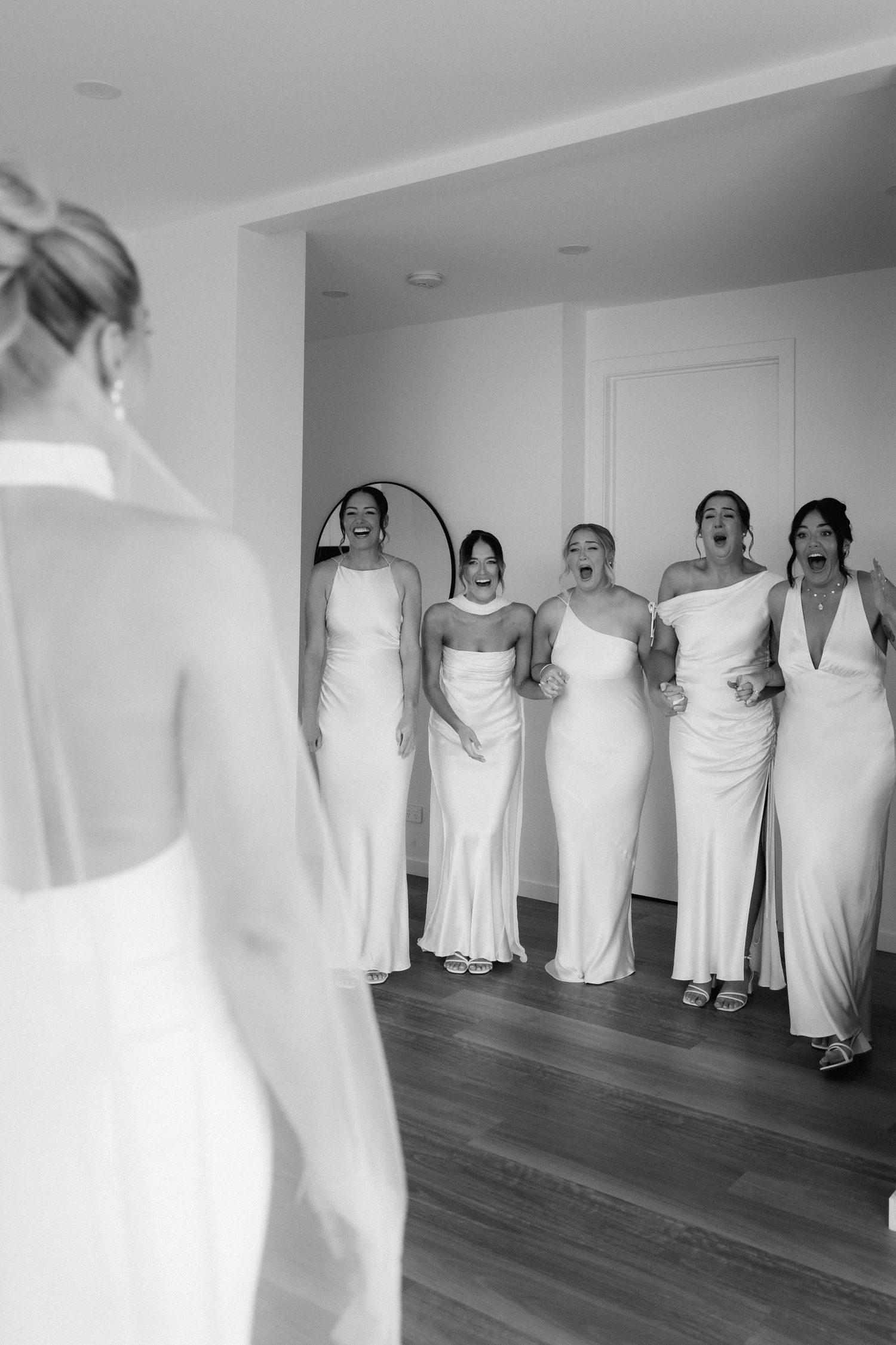 Wedding party in elegant white dresses standing in formation in a bright room.