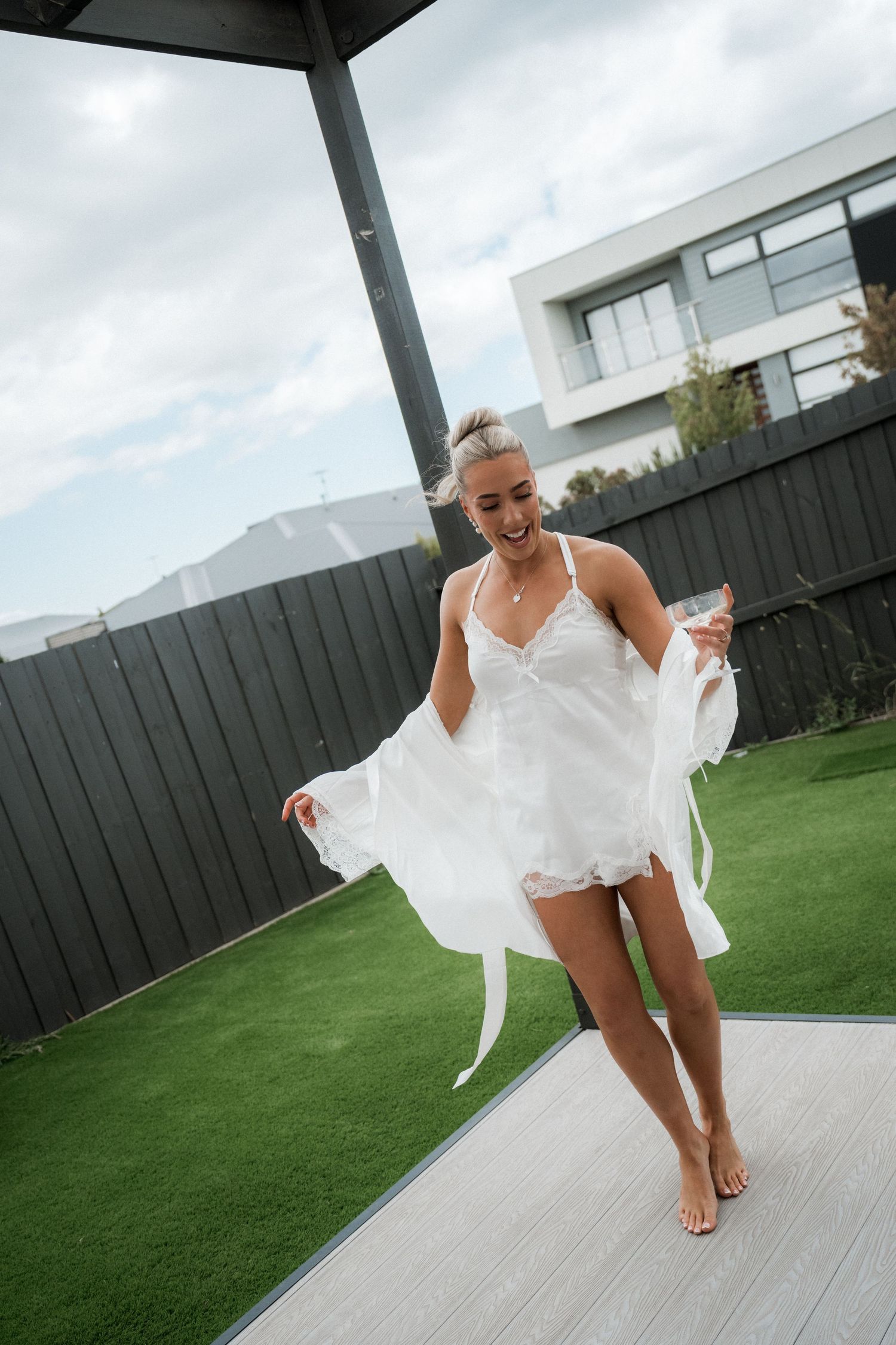 A playful outdoor bridal photoshoot on a green lawn with flowing white dress movement.