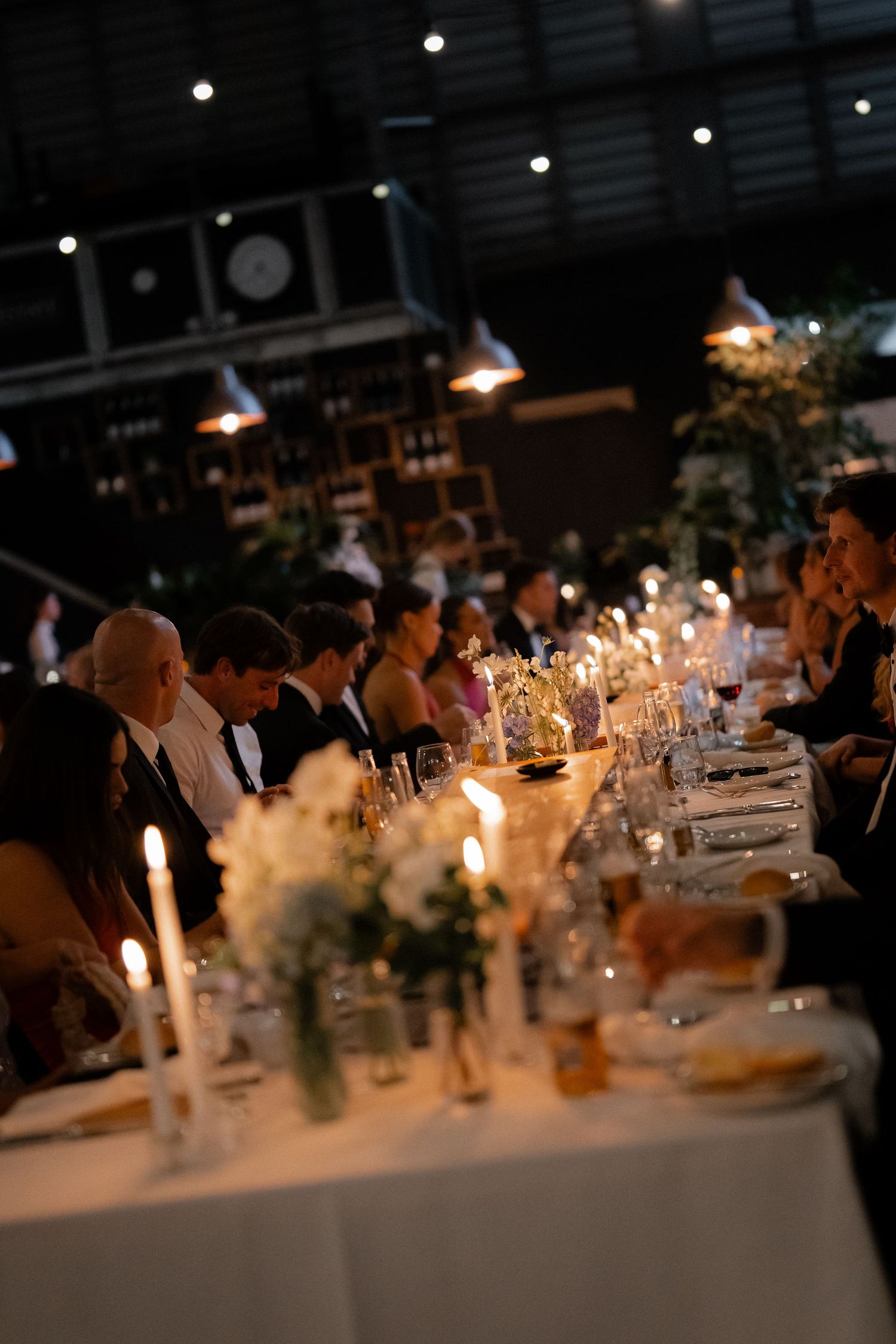 Candlelit wedding reception tables decorated with elegant floral centerpieces and ambient lighting.