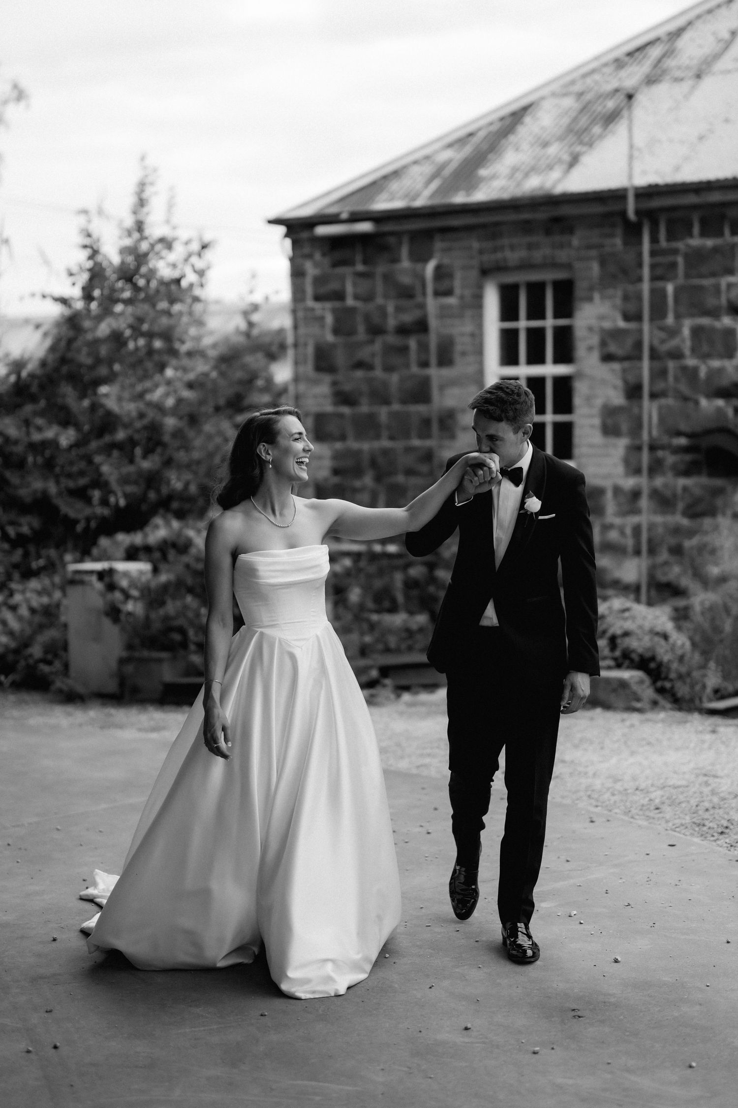 Black and white photos show playful moments between newlyweds outside stone buildings.