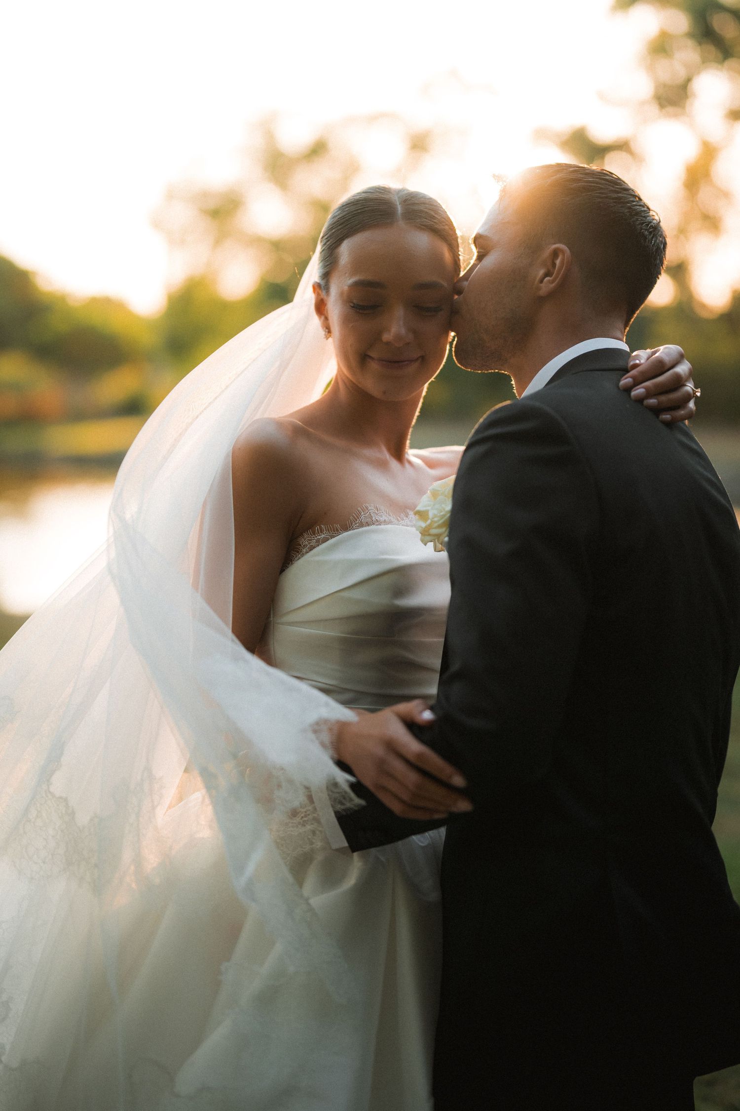Romantic sunset wedding portraits with flowing veil and intimate embraces.