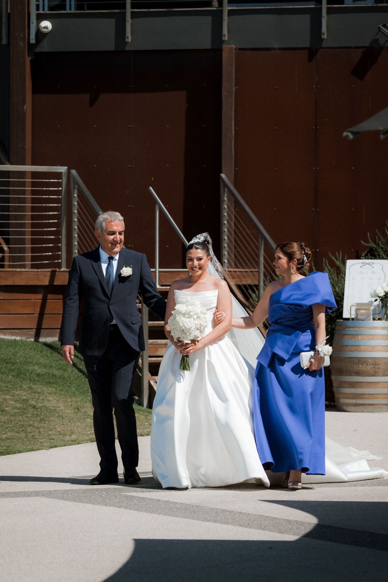 A wedding party walks outside with the bride in white and an attendant in royal blue.