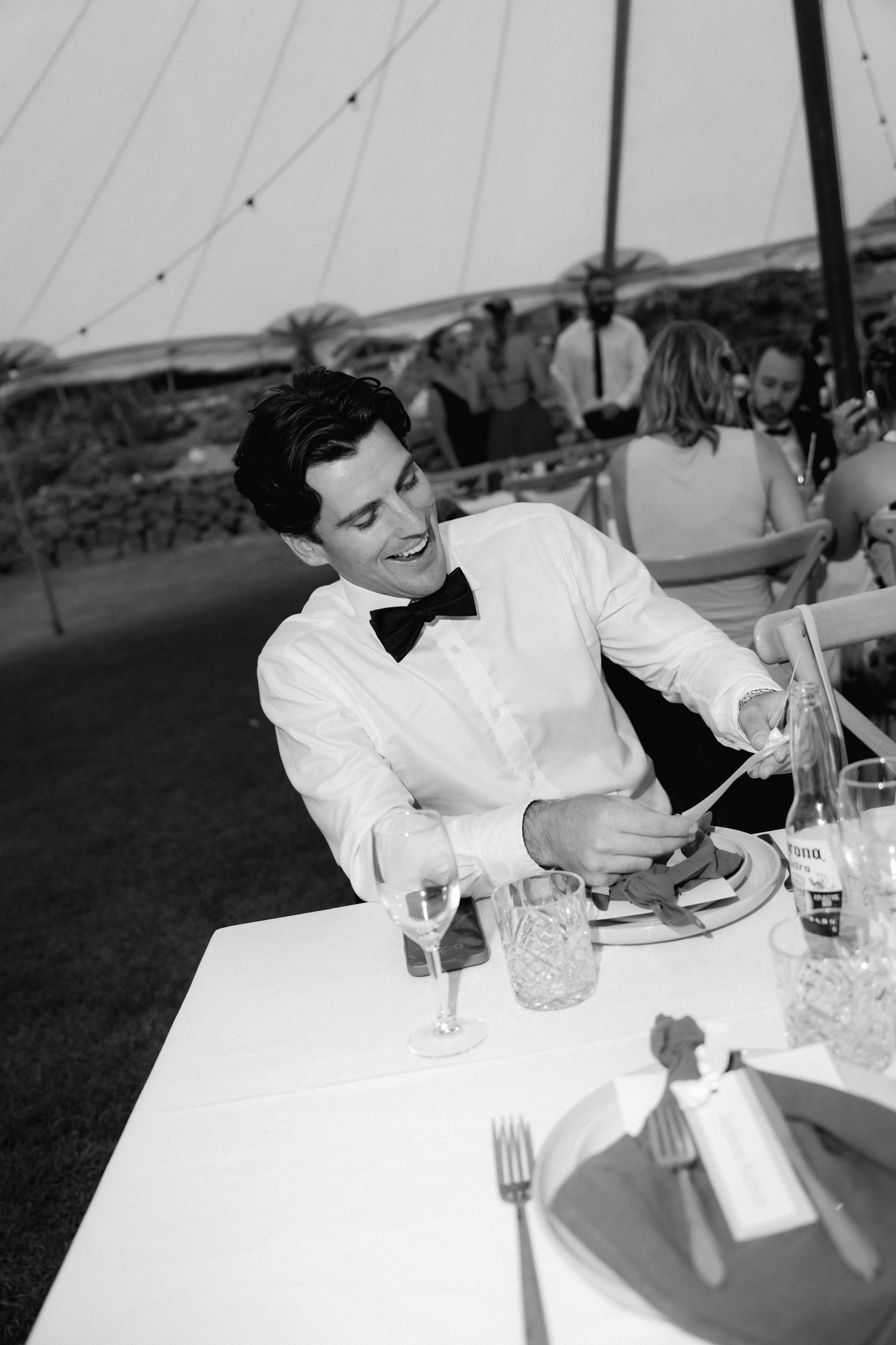 Black and white photo of guest enjoying dinner at outdoor reception.