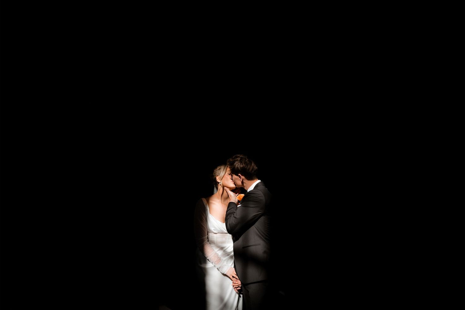 Two identical white birds face each other in a graceful dance-like pose, reflecting against a dark background.