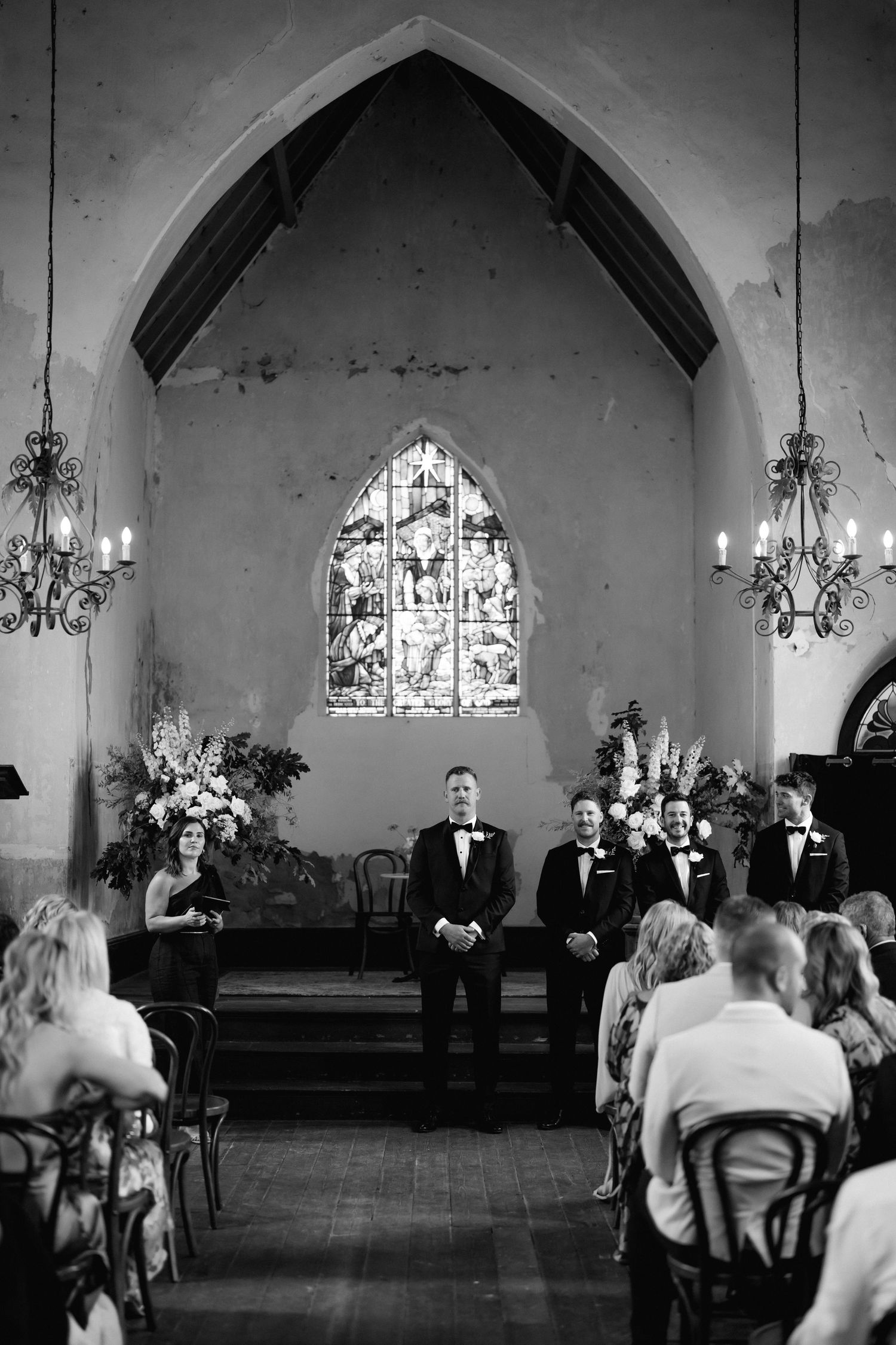 Wedding ceremony takes place in a beautiful church interior with Gothic arches and stained glass windows.