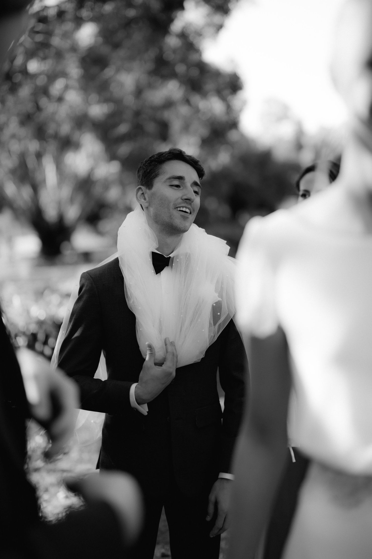 Black and white candid shot of a wedding celebration with guests in formal attire.