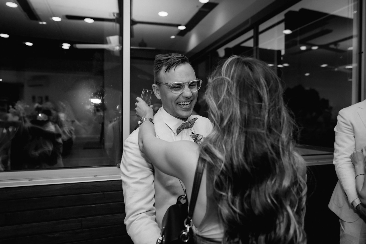 Black and white photo of wedding reception celebrations in an indoor venue.