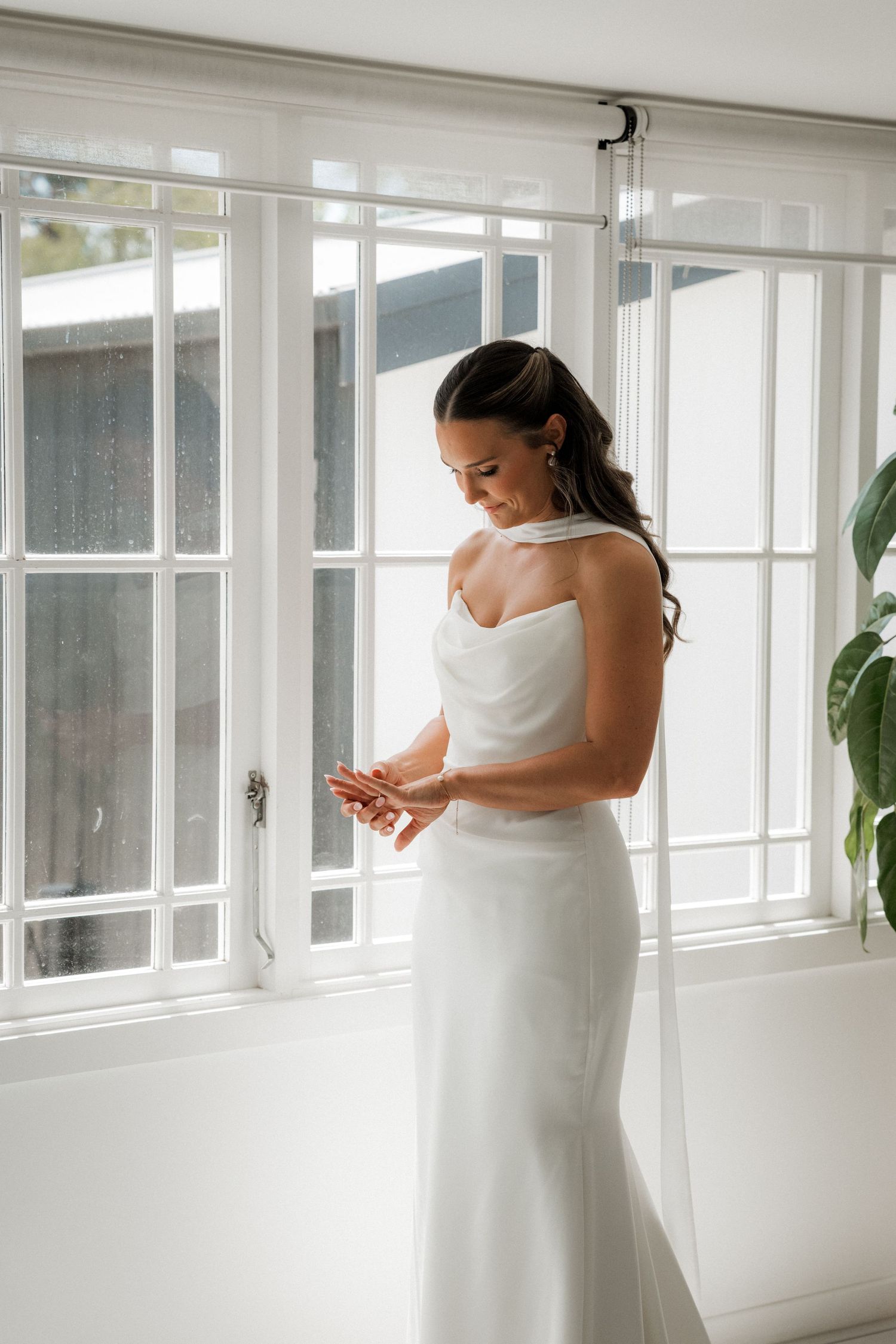 Elegant bridal preparation scene in a bright sunlit room with white windows.
