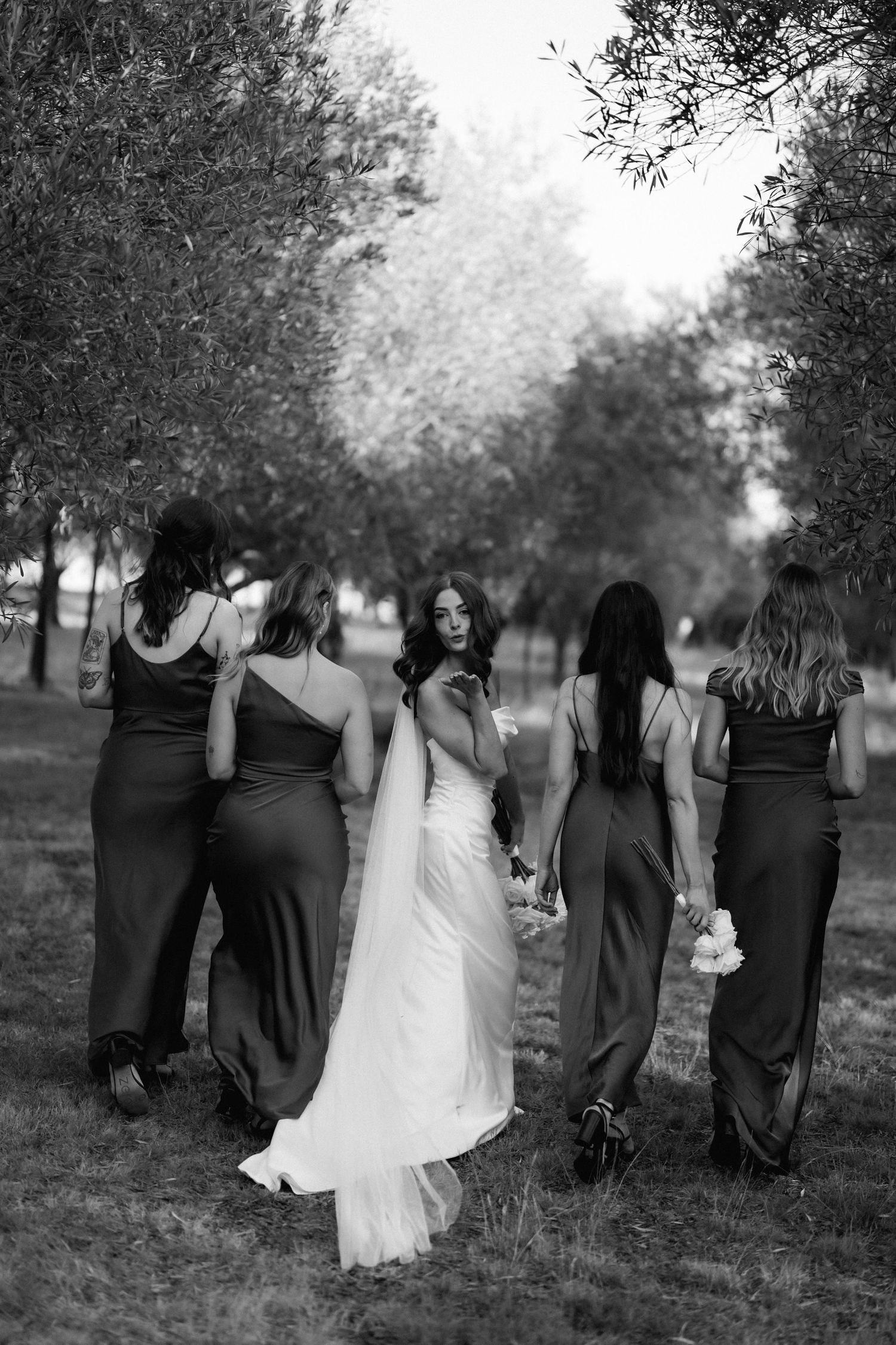 Black and white photo of wedding party walking together through a scenic outdoor setting.