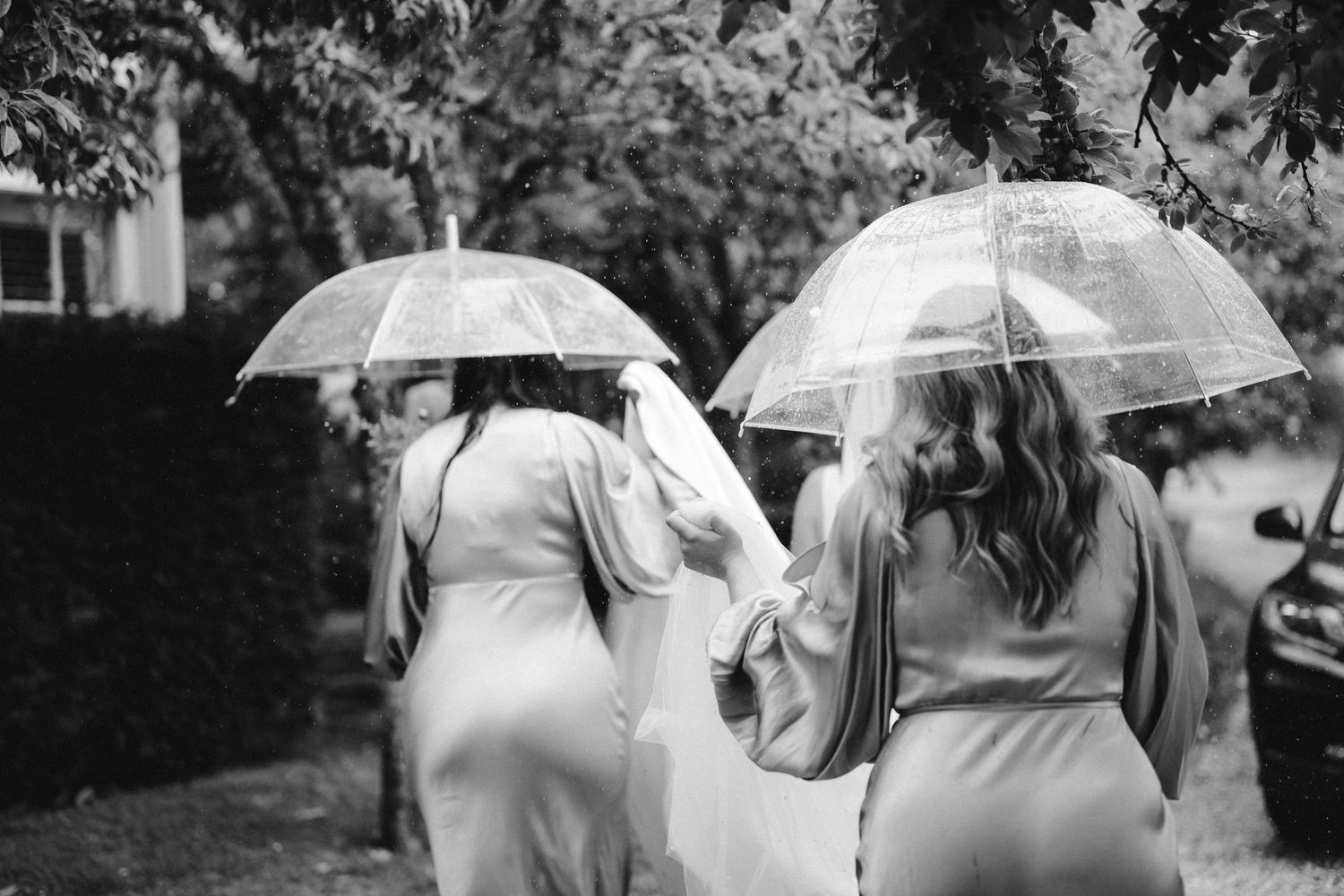 People walking together holding clear umbrellas in the rain during an outdoor event in black and white photography.